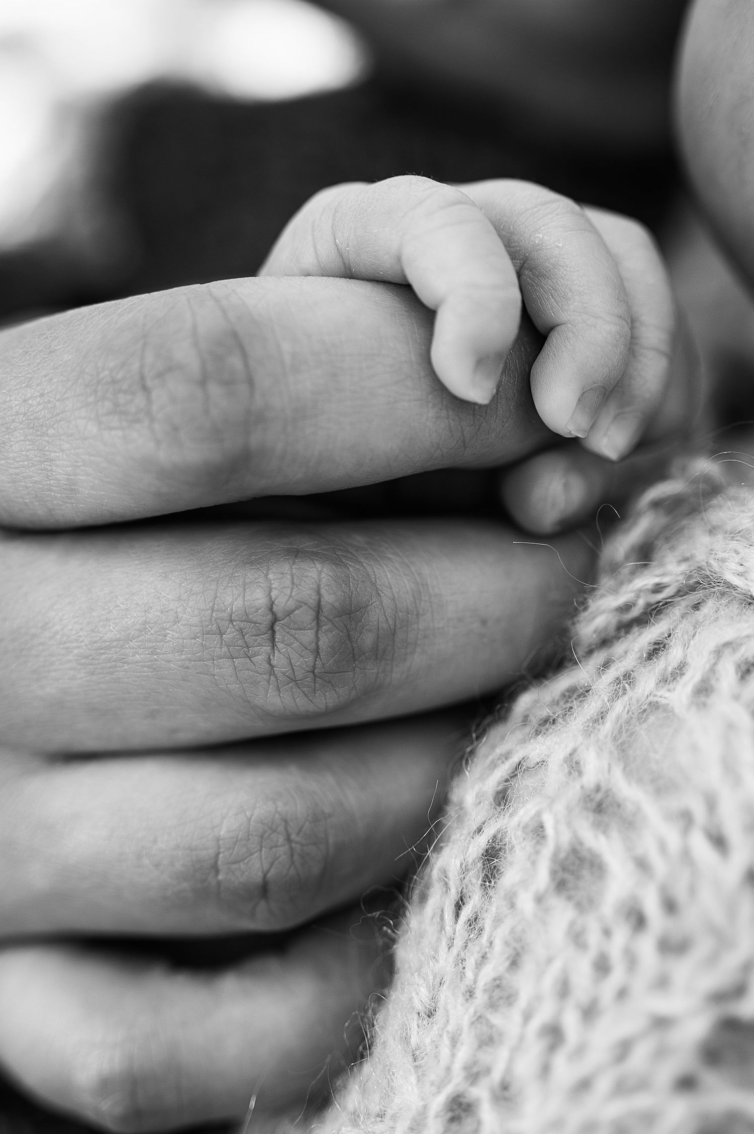 Black and white close-up of a newborn holding a parent’s finger—timeless storytelling imagery from a newborn photography session.