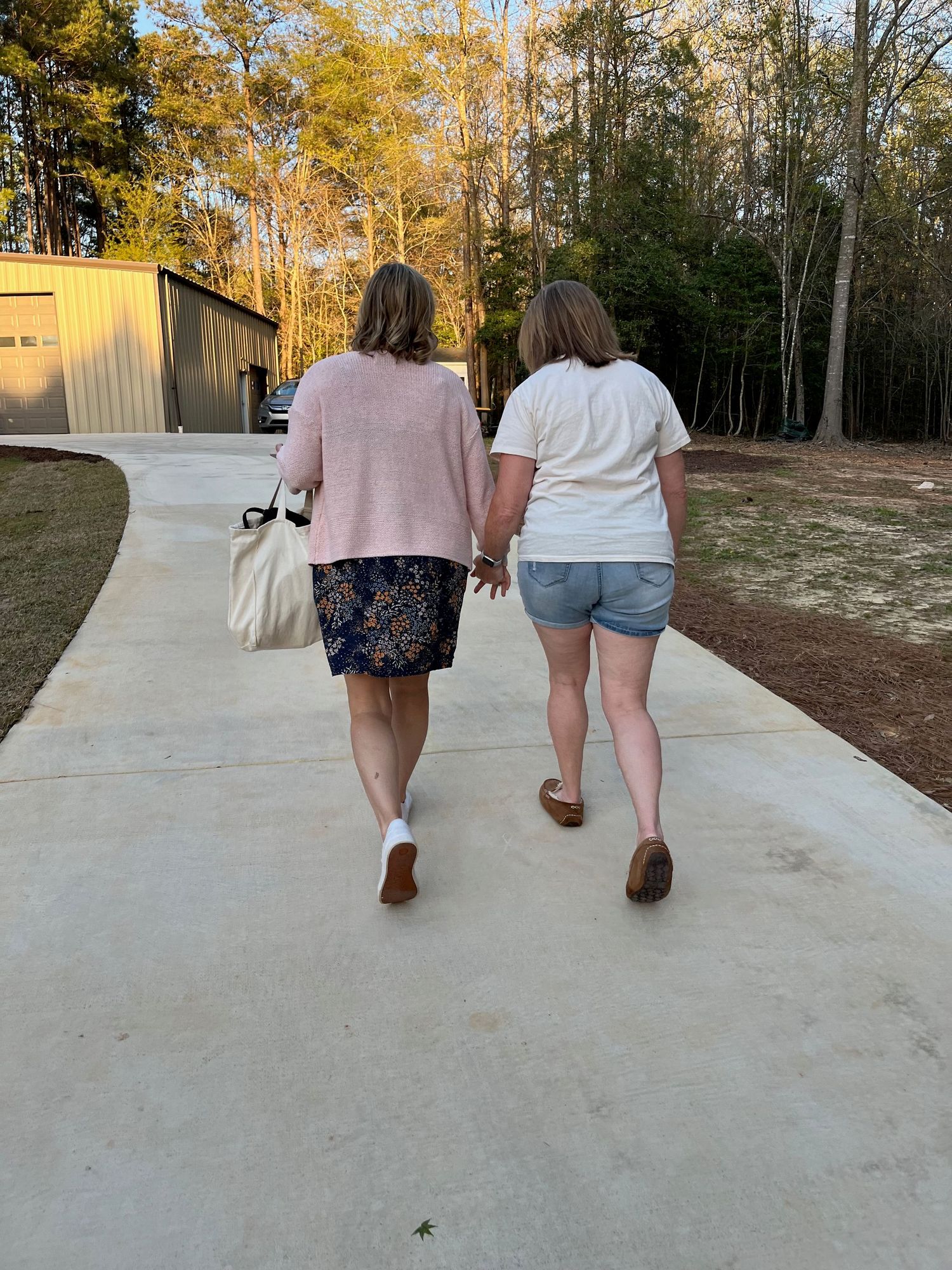 A sweet moment between two women walking hand in hand at golden hour — joy and connection in everyday moments.
