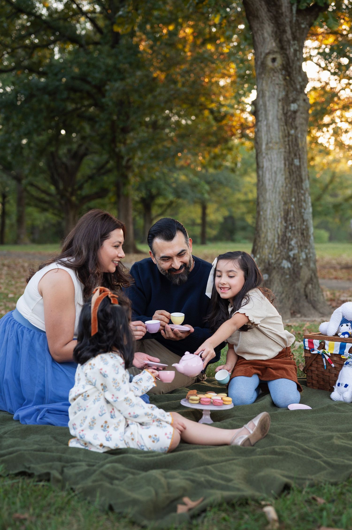 Westerville family photographer documents parents and daughters pouring pretend tea together on a picnic blanket at Sharon Woods.