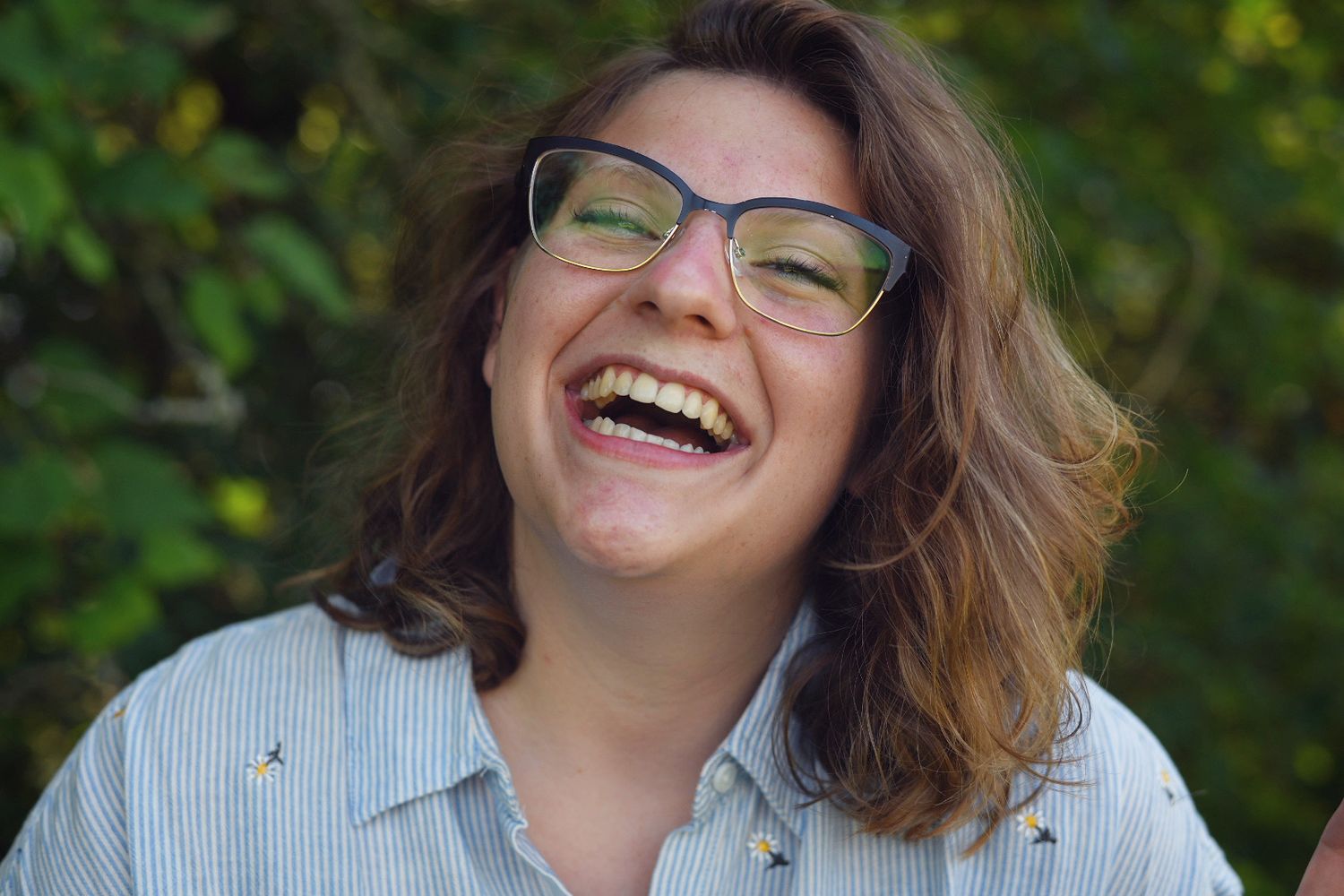 Close-up of a woman laughing with boundless joy during a relaxed outdoor headshot session.