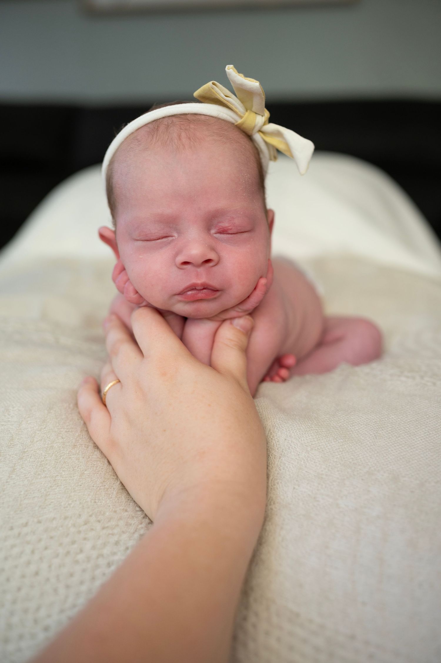 Behind-the-scenes newborn photography safety shot with hands supporting baby in froggy pose.
