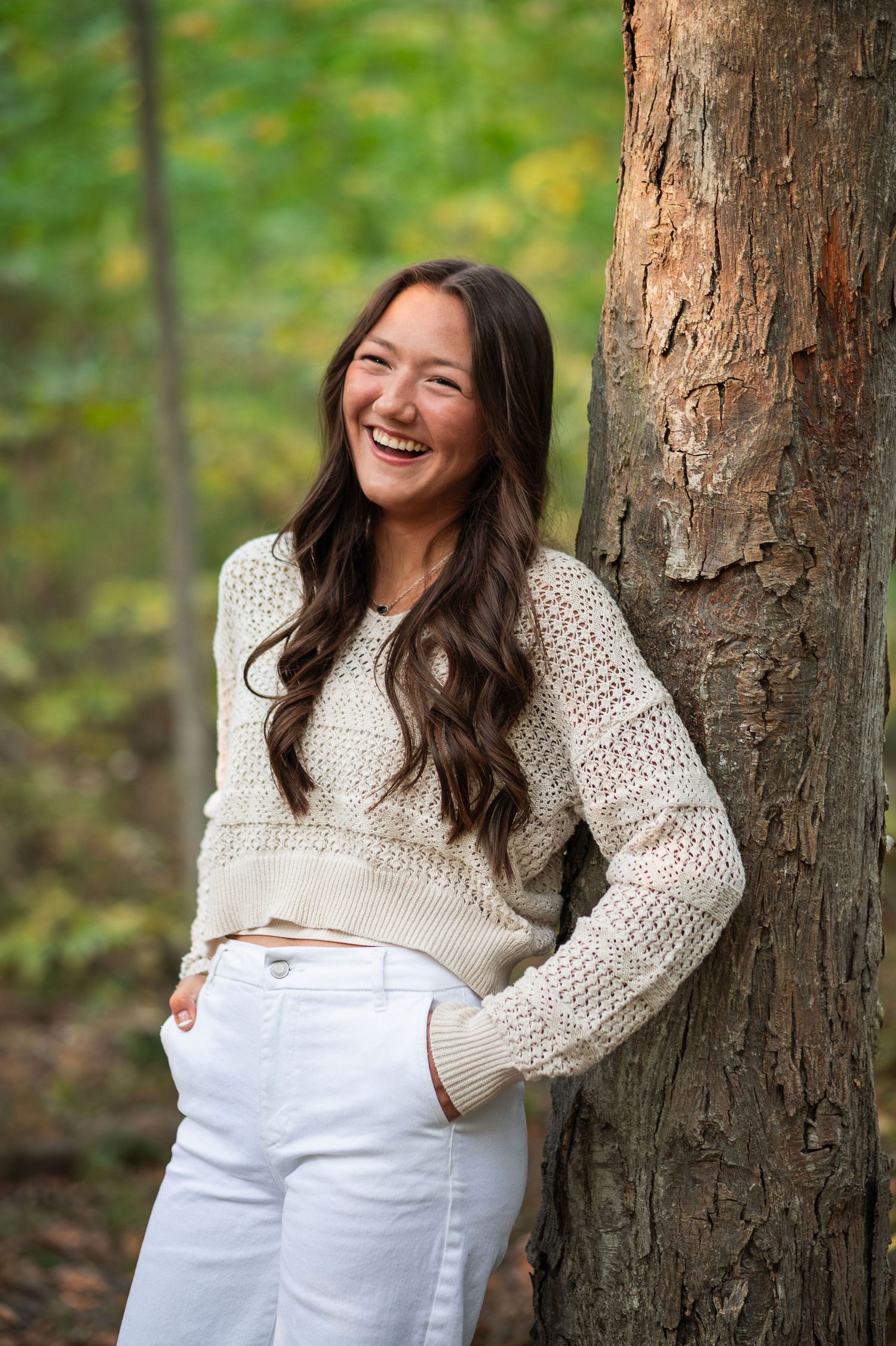 High school senior smiles in golden light, leaning against a tree during a senior session in Westerville, Ohio.