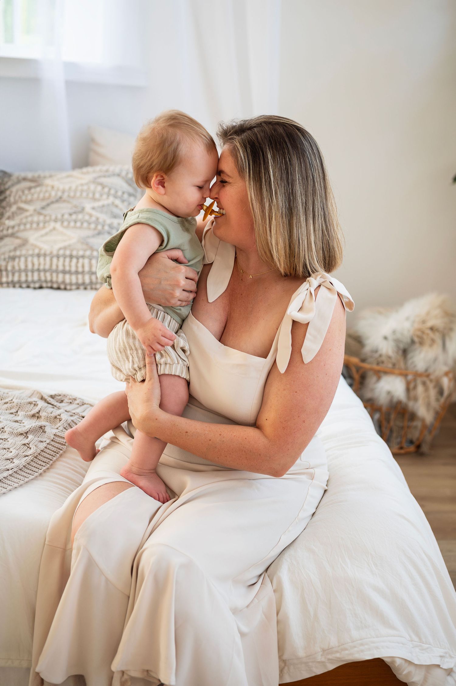 Candid in-home session—mother and toddler share a sweet nose-to-nose snuggle in soft natural light