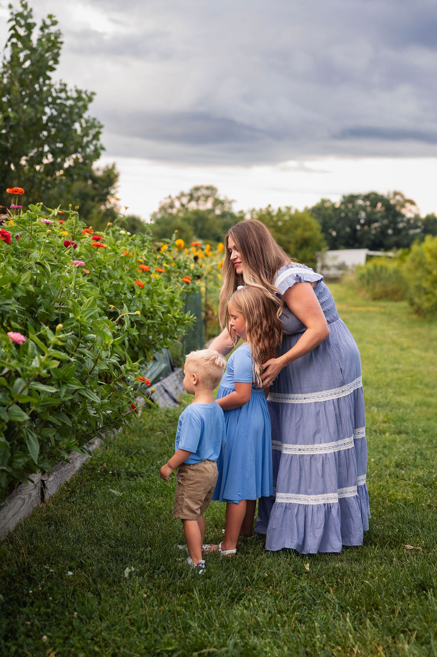 Mom with two kids looking at wildflowers on a farm near Westerville—Columbus family session