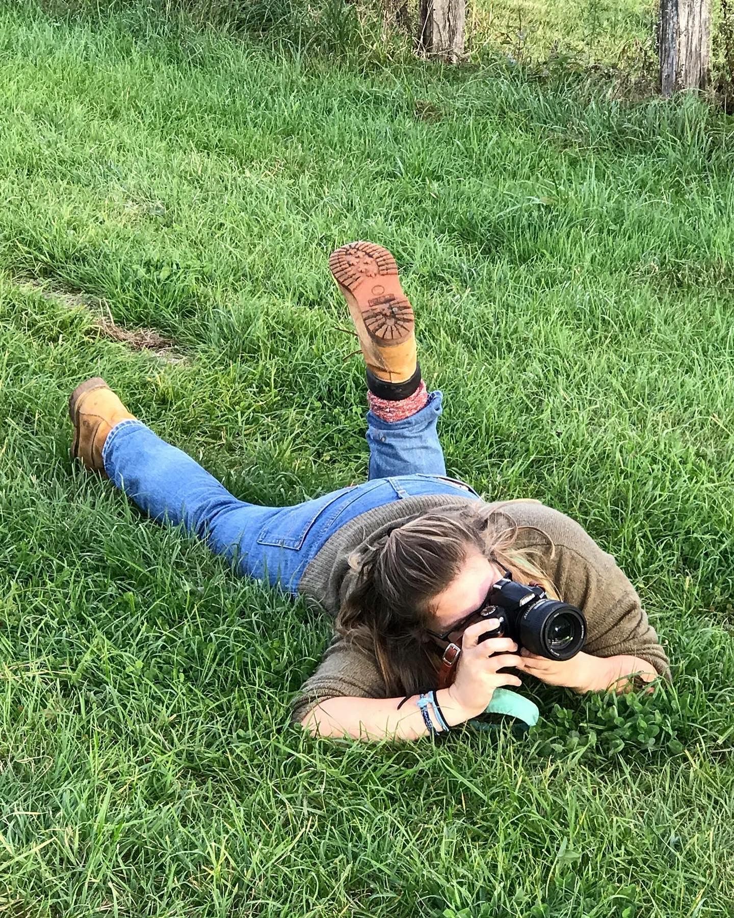 Maddie Lewis, Westerville family photographer, gets low to capture a playful shot during an outdoor session in a grassy field.