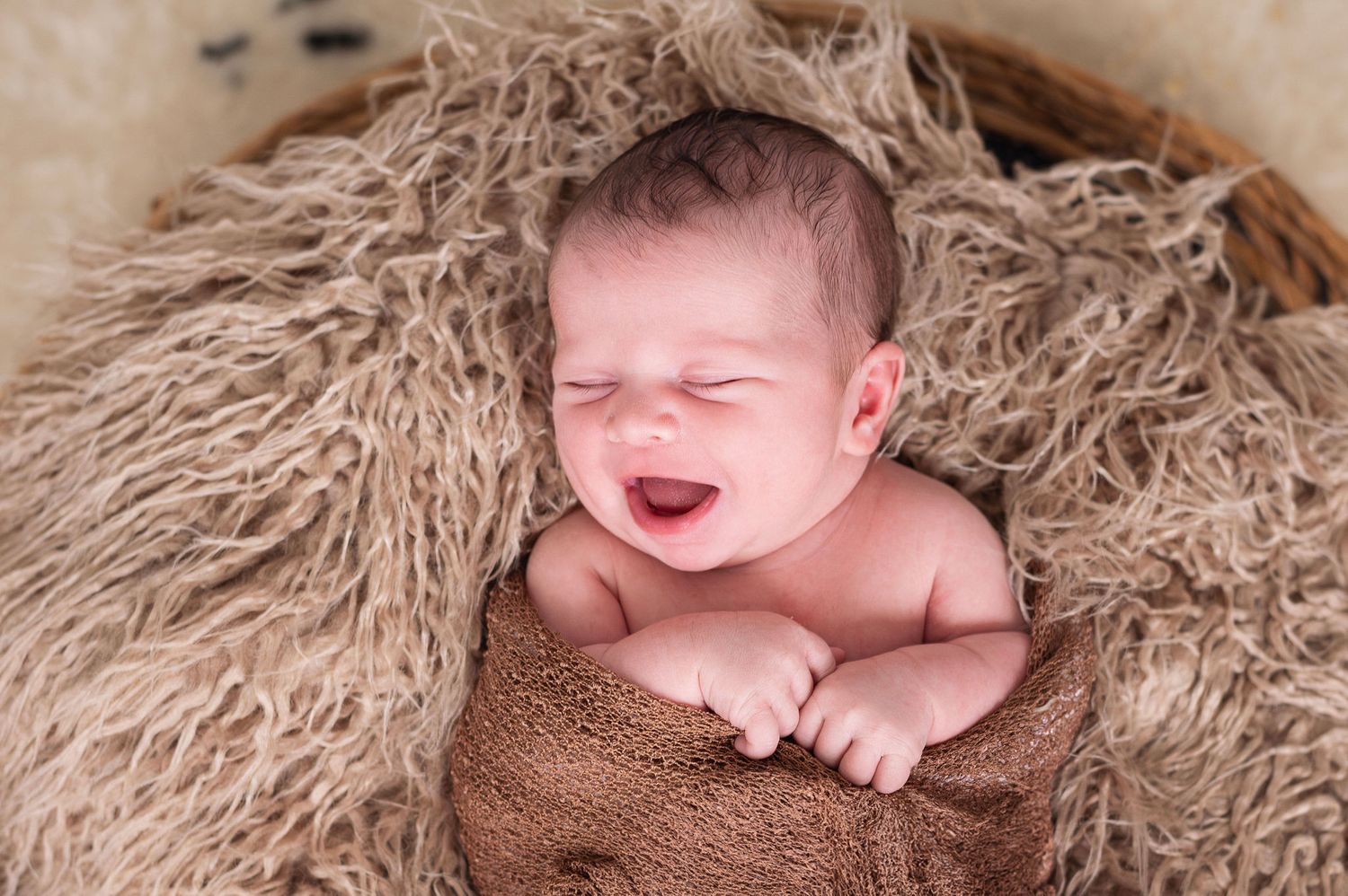 Newborn wrapped and smiling in cozy textured blanket—studio session with Westerville newborn photographer