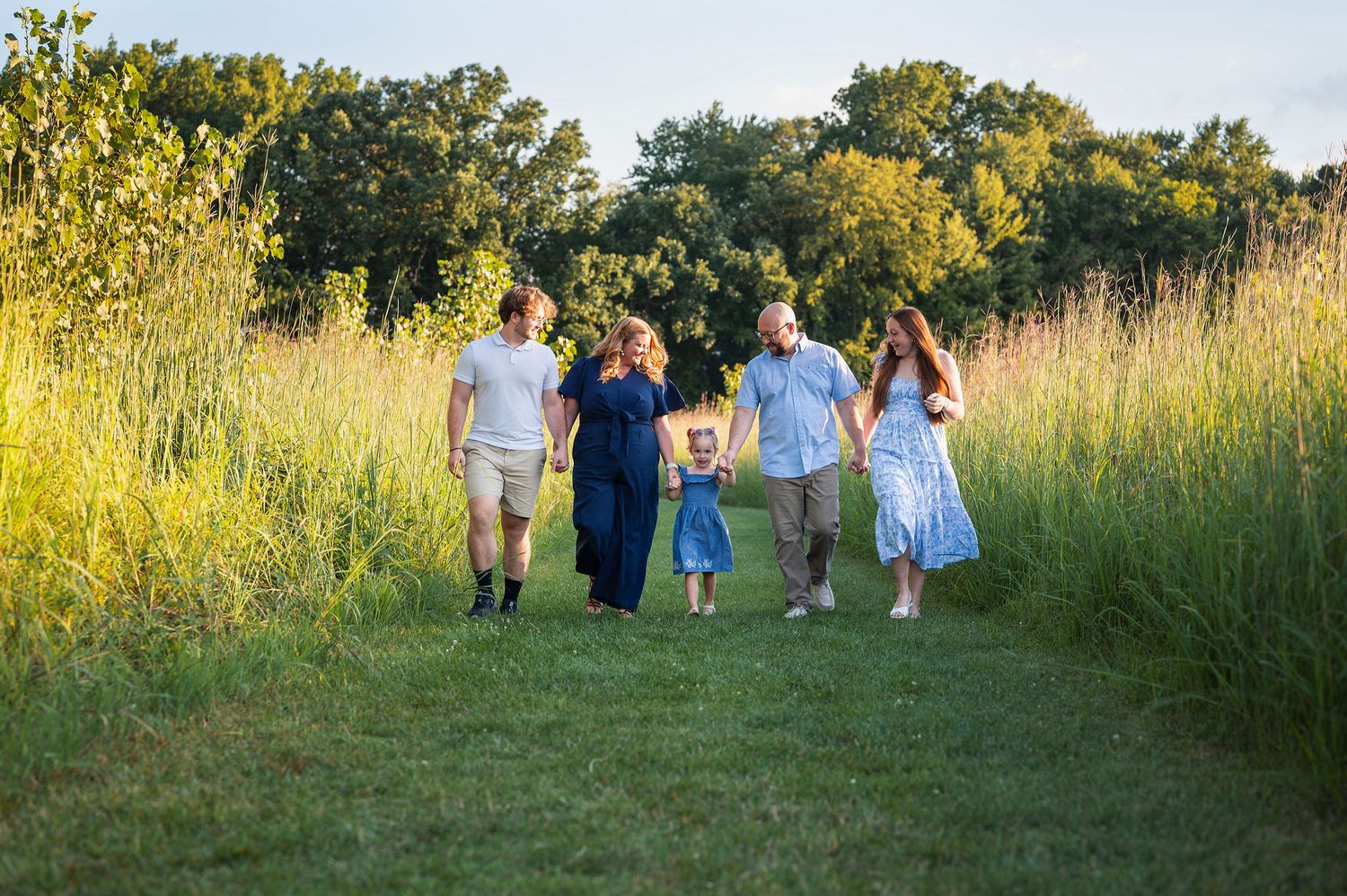 Family walking hand in hand at Rocky Fork Metro Park during golden hour—captured by Westerville family photographer