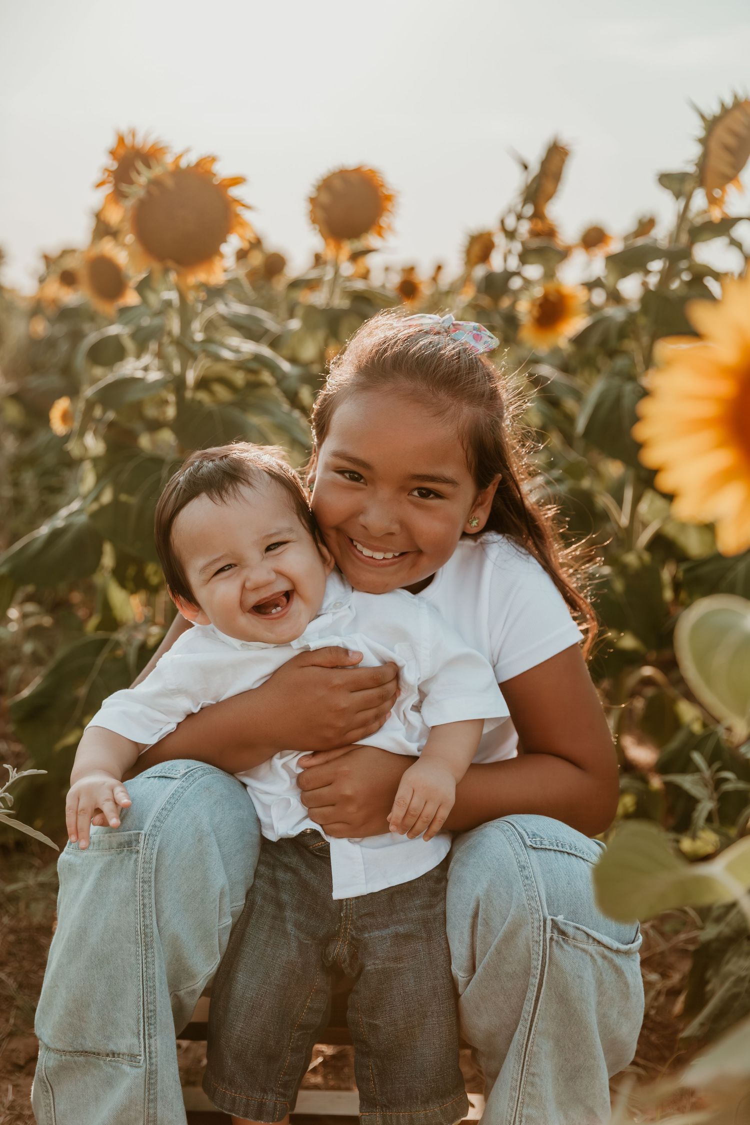 A joyful family moment captured in a sunflower field at sunset, showing pure happiness and genuine laughter.