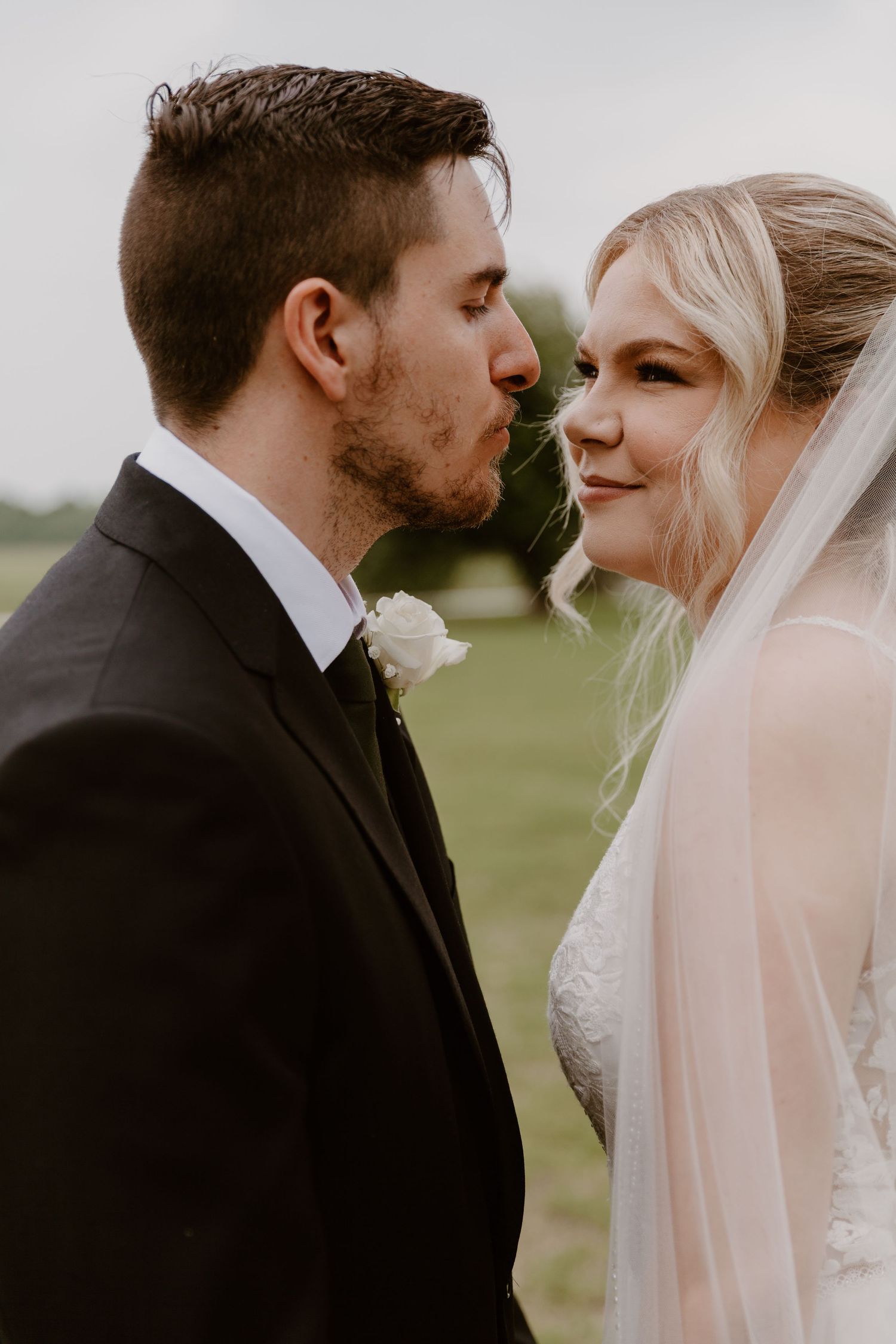 A romantic wedding moment captured of a couple in formal attire sharing an intimate moment outdoors.