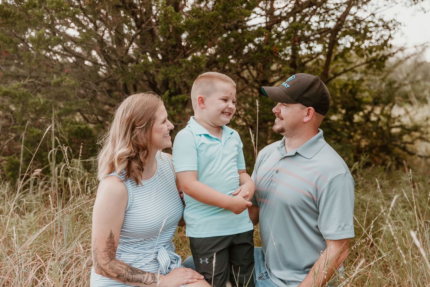 A group shares joyful moments in a field at sunset wearing coordinating blue outfits.