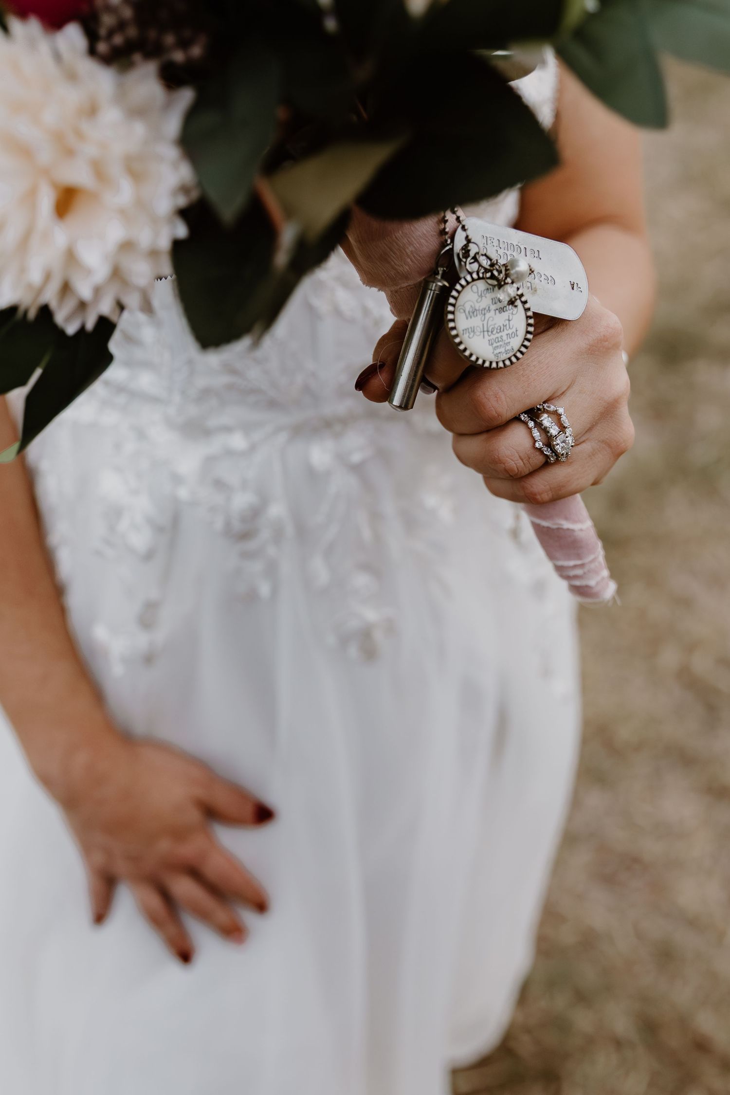 Close-up view of ornate silver rings on hands against a white lace wedding dress background.