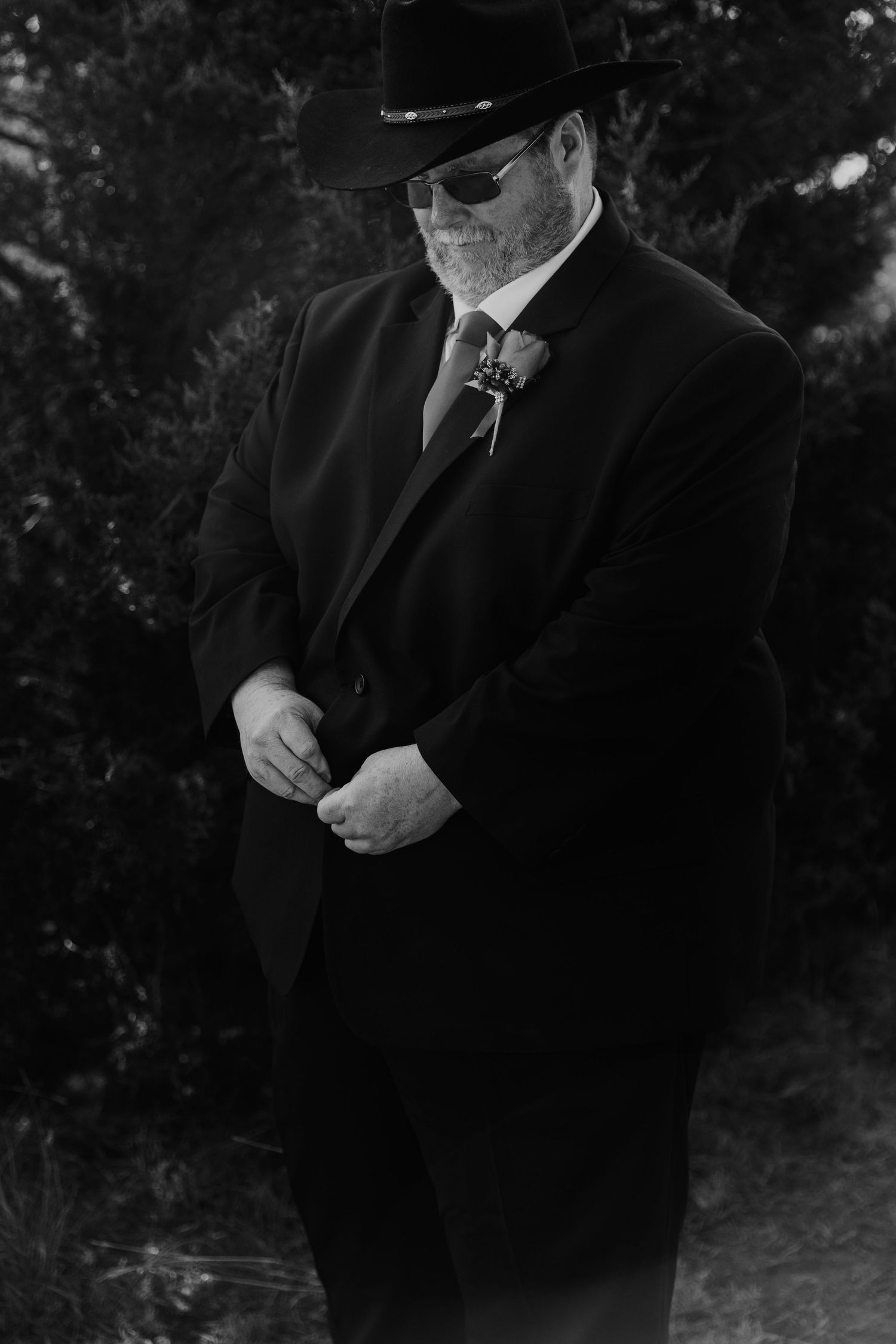 Series of black and white photos showing groomsmen in dark suits adjusting their attire outdoors.