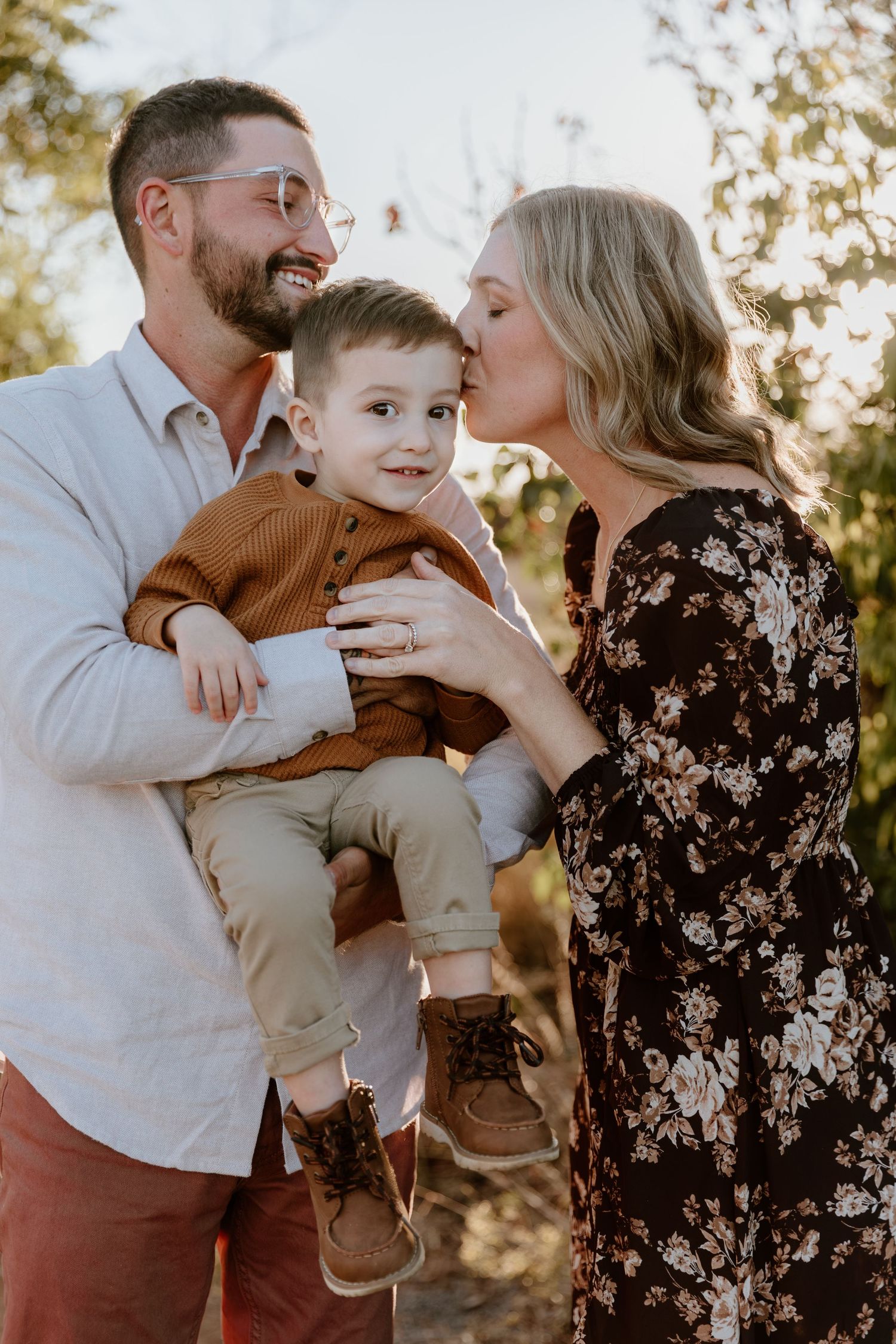 A family shares a tender outdoor moment together at sunset, with warm autumn colors in the background.