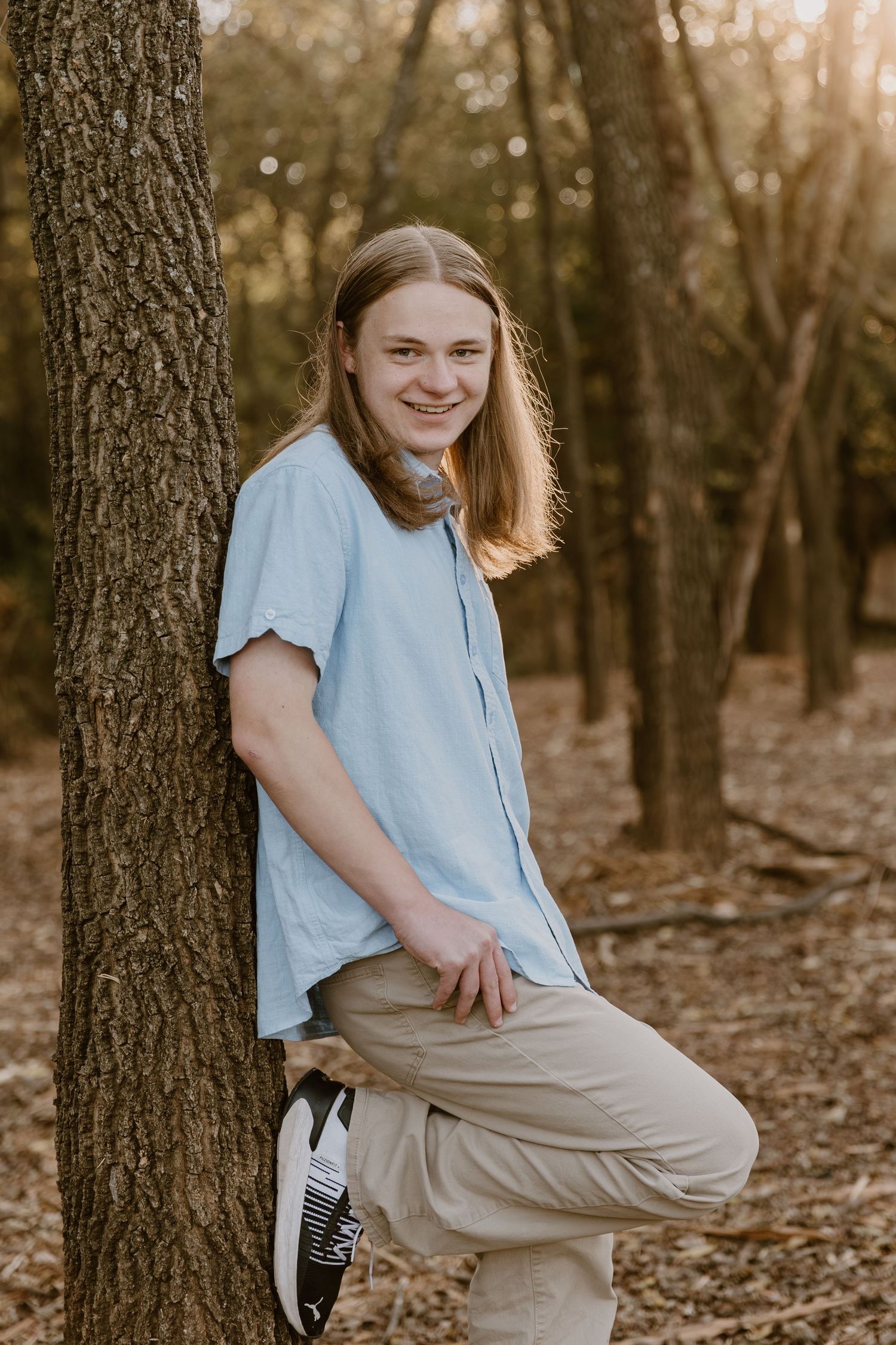 A series of outdoor portraits taken in a wooded area with fallen leaves, featuring someone in a light blue shirt and khakis.