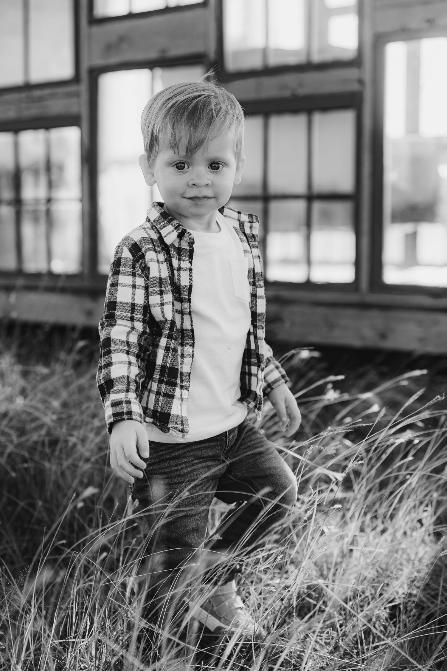 A series of black and white photos showing someone in plaid and jeans standing in tall grass.