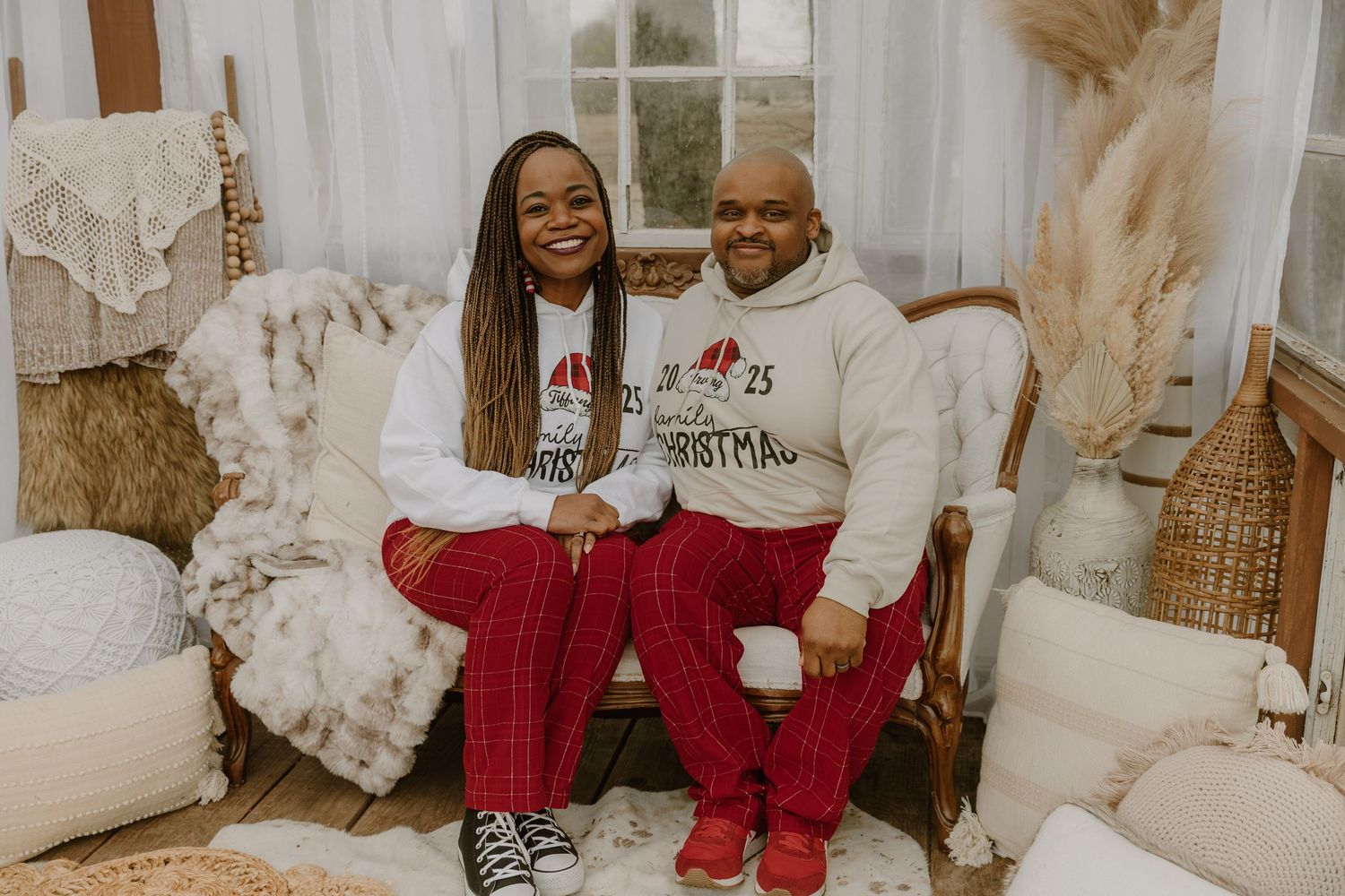 Family wearing matching red and white holiday pajamas sits together on a couch surrounded by Christmas decor.