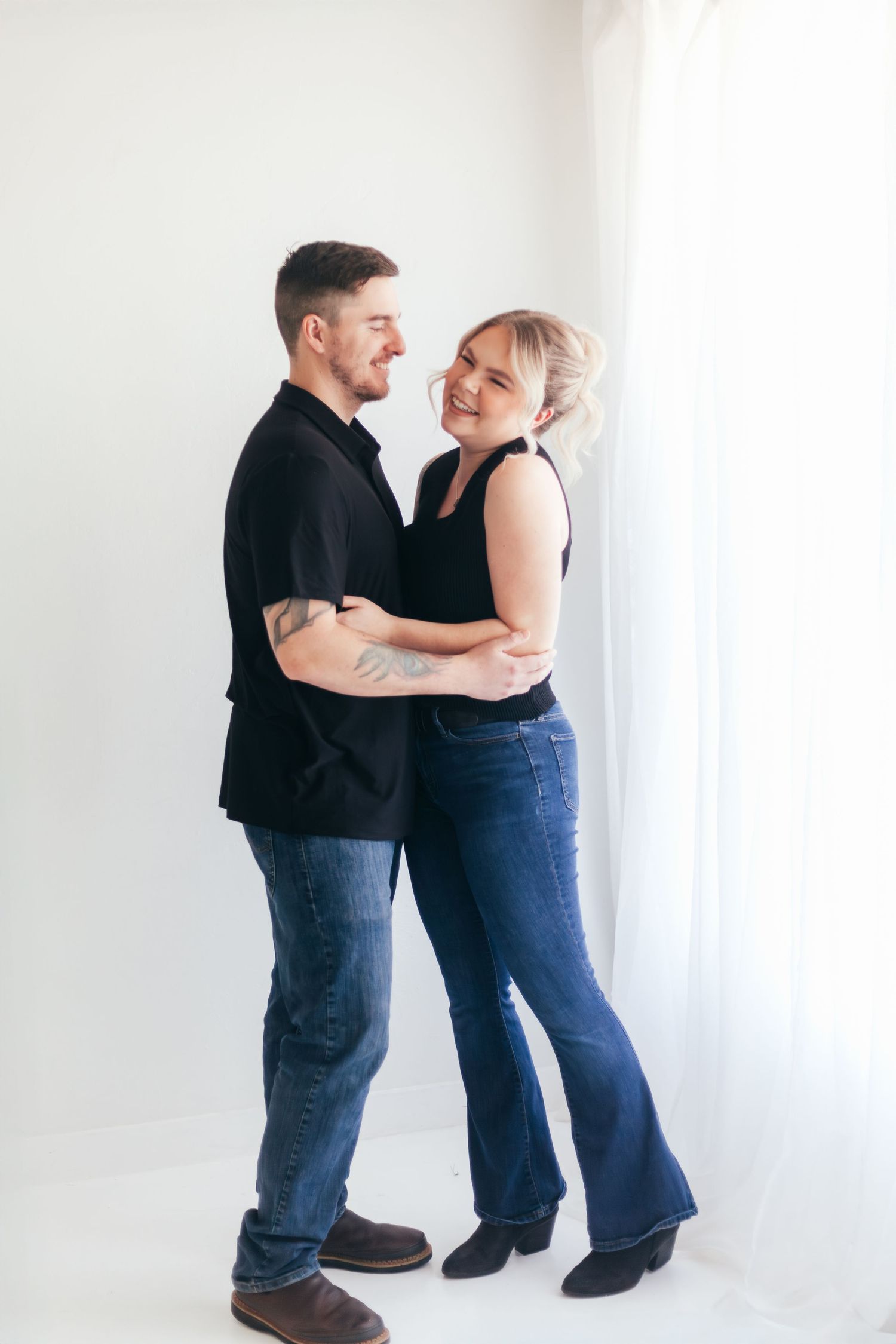 Happy couple embracing and laughing during casual portrait session.