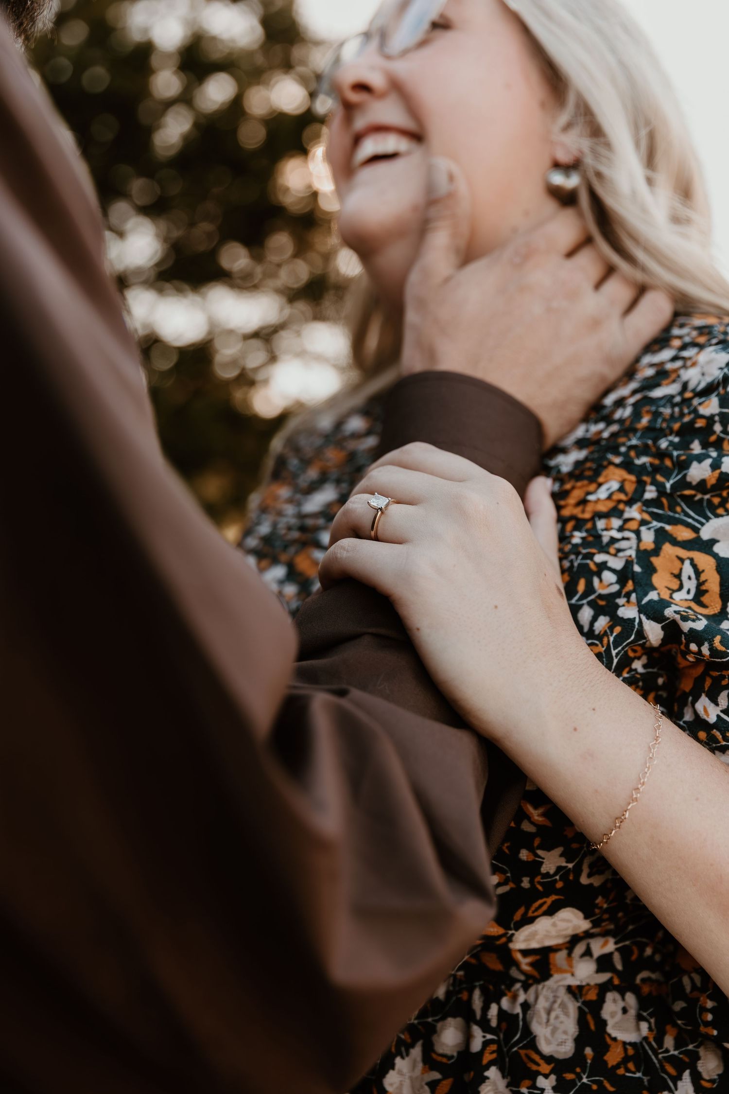 Close-up shot of hands embracing during an intimate outdoor moment with floral dress details visible.