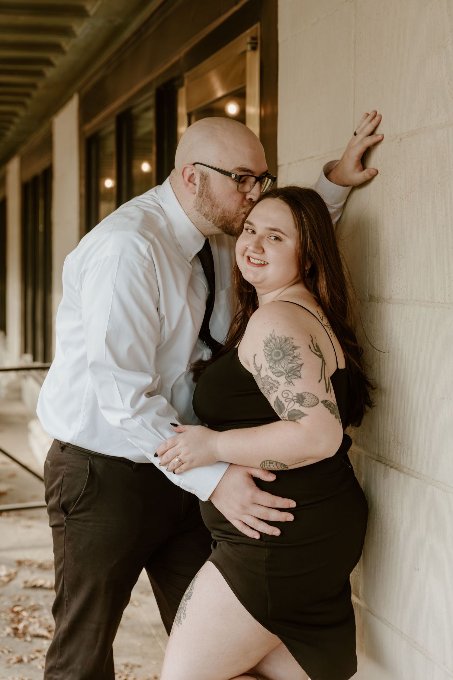 A romantic couple embraces in a series of intimate black and white engagement photos along a building's exterior.