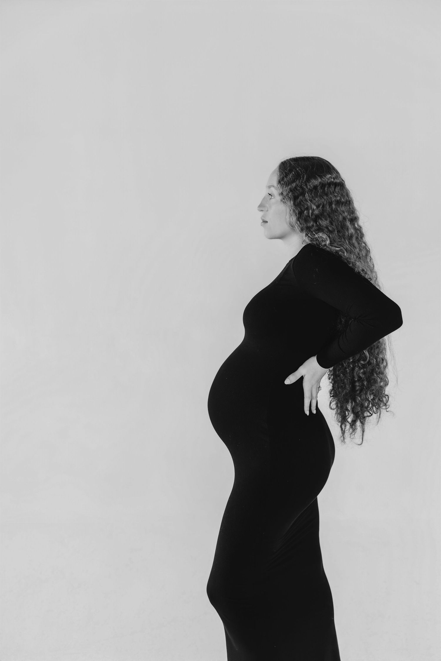 A black and white series of silhouettes showing a pregnant person's profile in different poses against a light background.