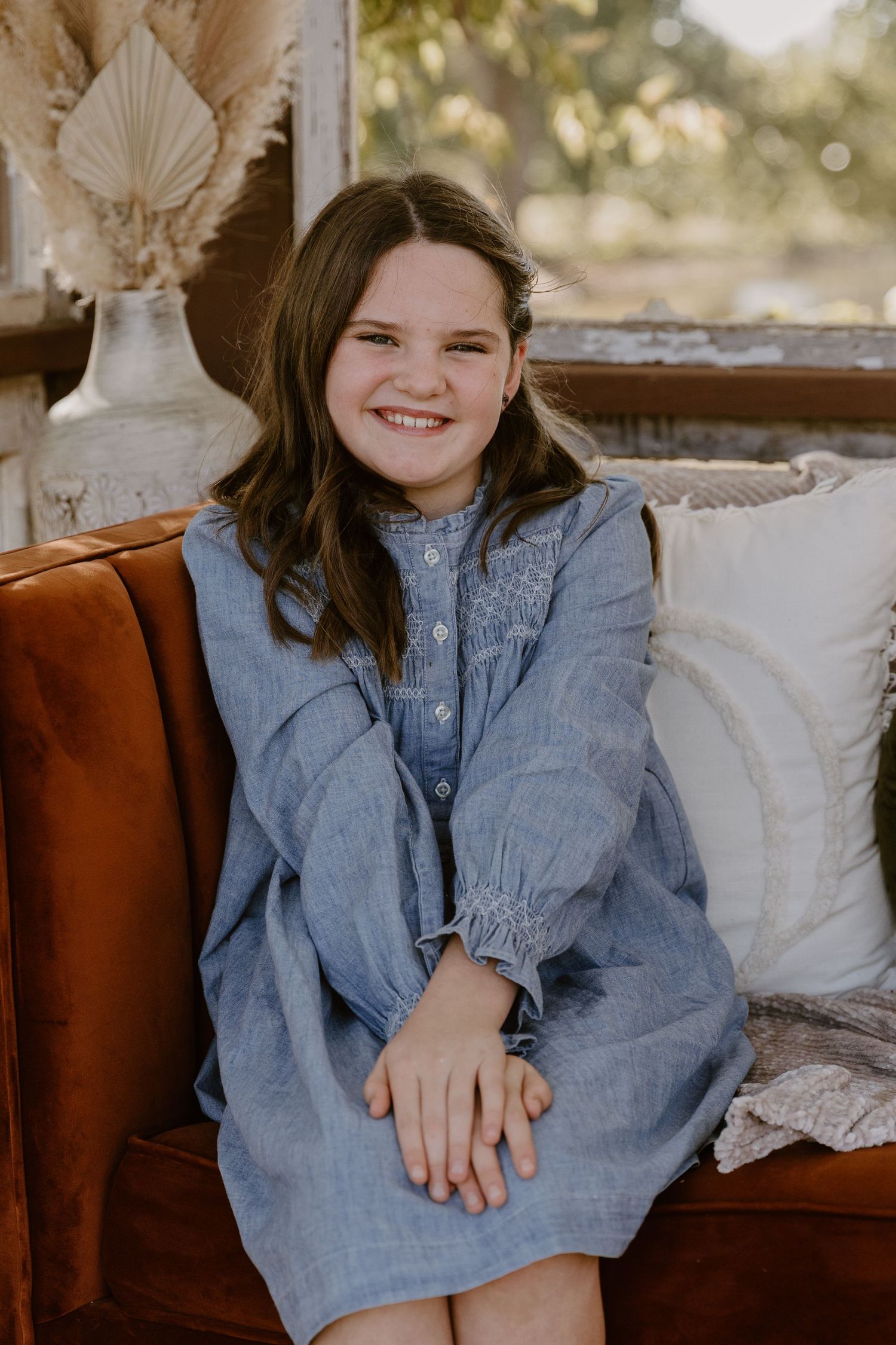 A series of photos showing someone wearing a light blue dress sitting on a brown leather couch with white pillows.