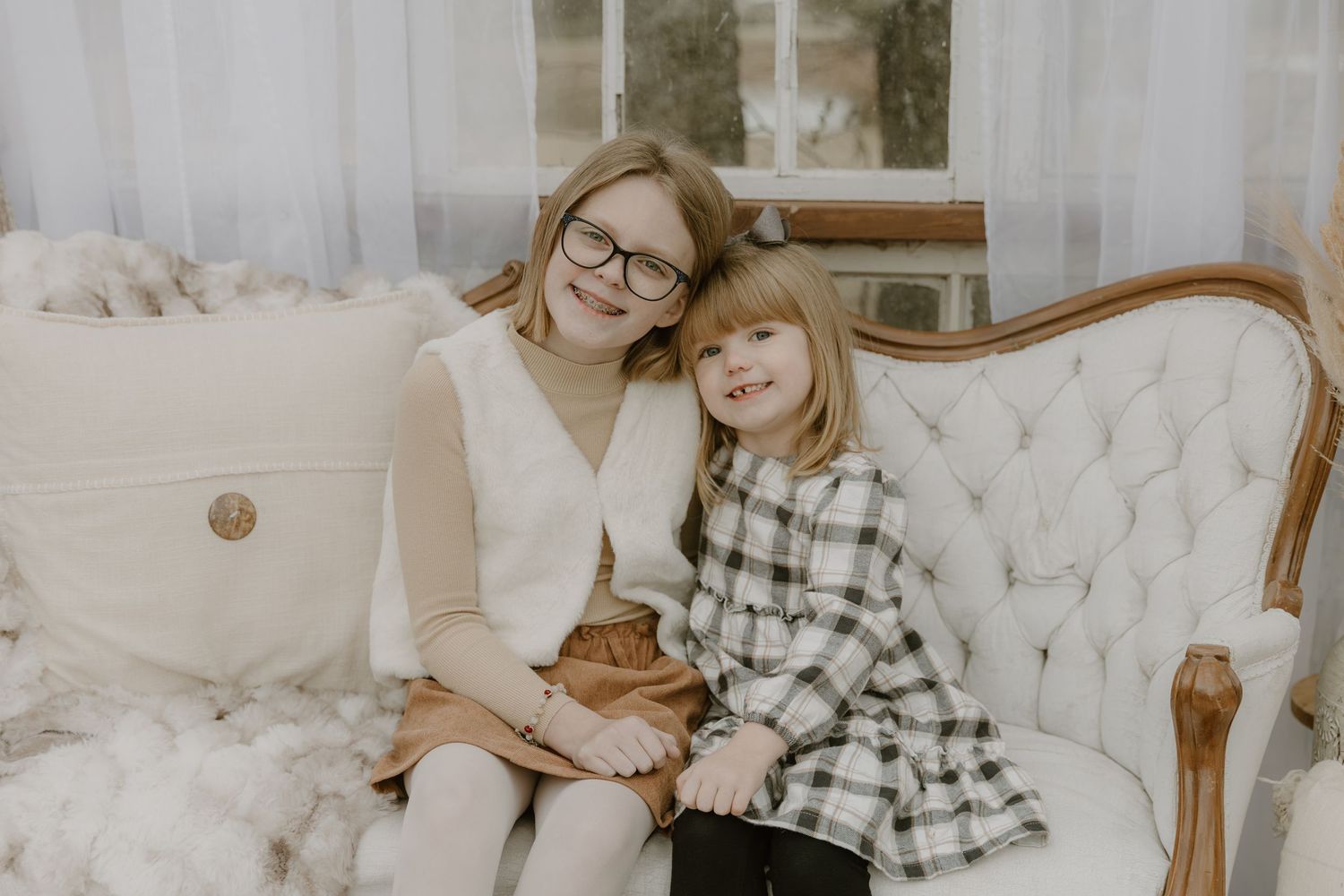 Cozy winter scene with plaid blanket and tufted white sofa in natural light.