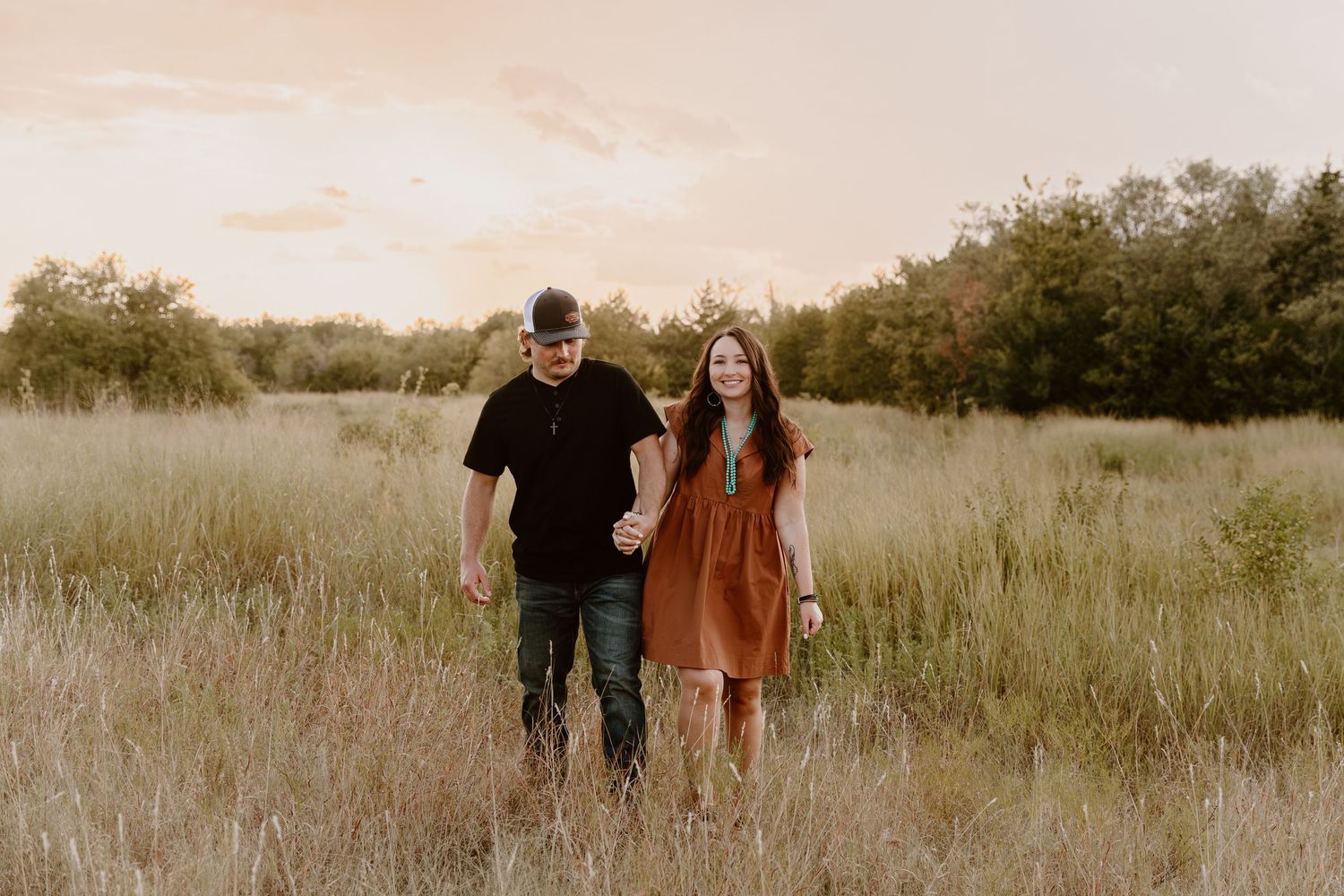 People walking together through a golden-hued grass field at sunset casting long shadows.