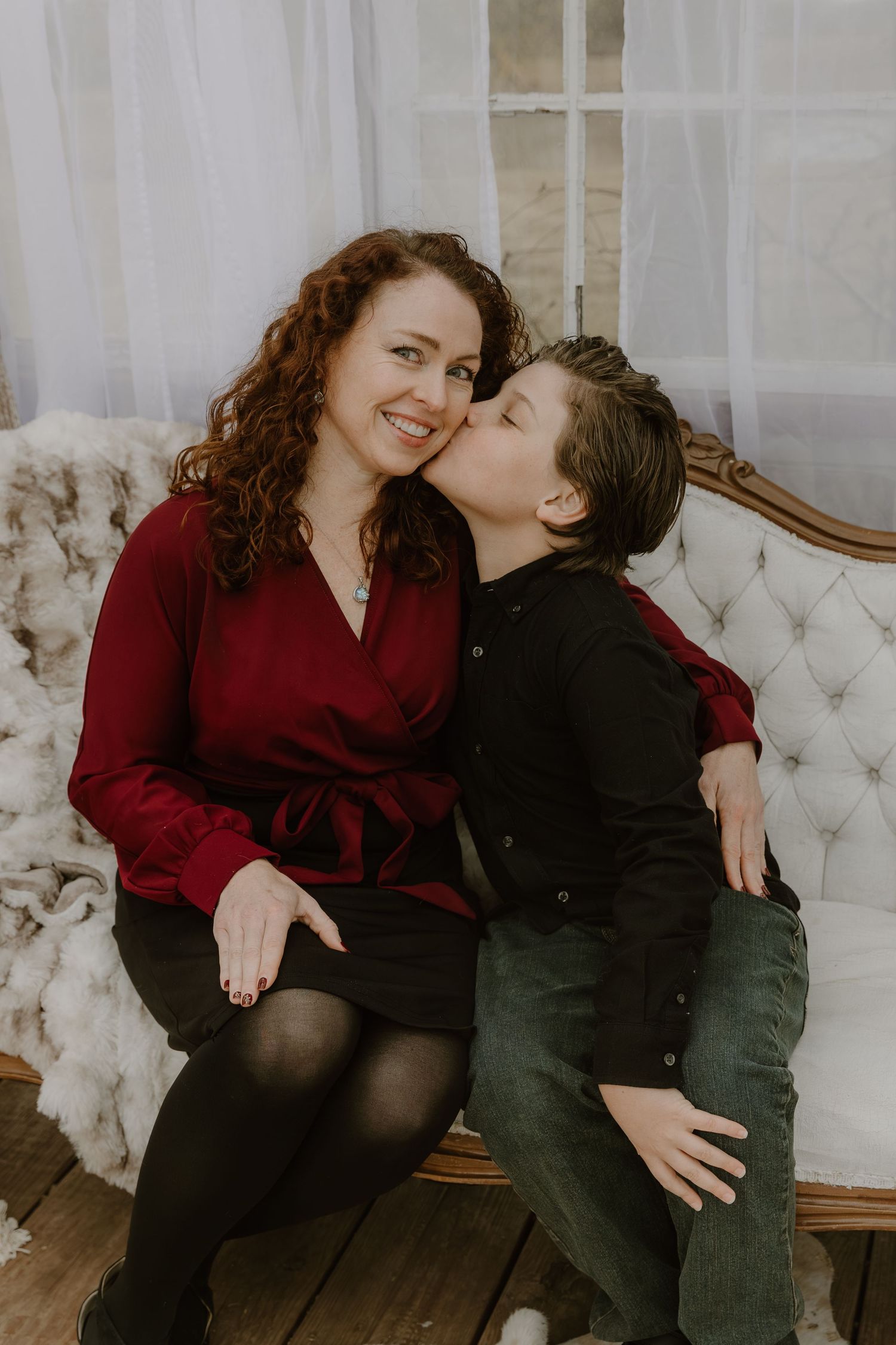 A couple shares intimate moments while sitting on a tufted white couch in a romantic indoor photoshoot.