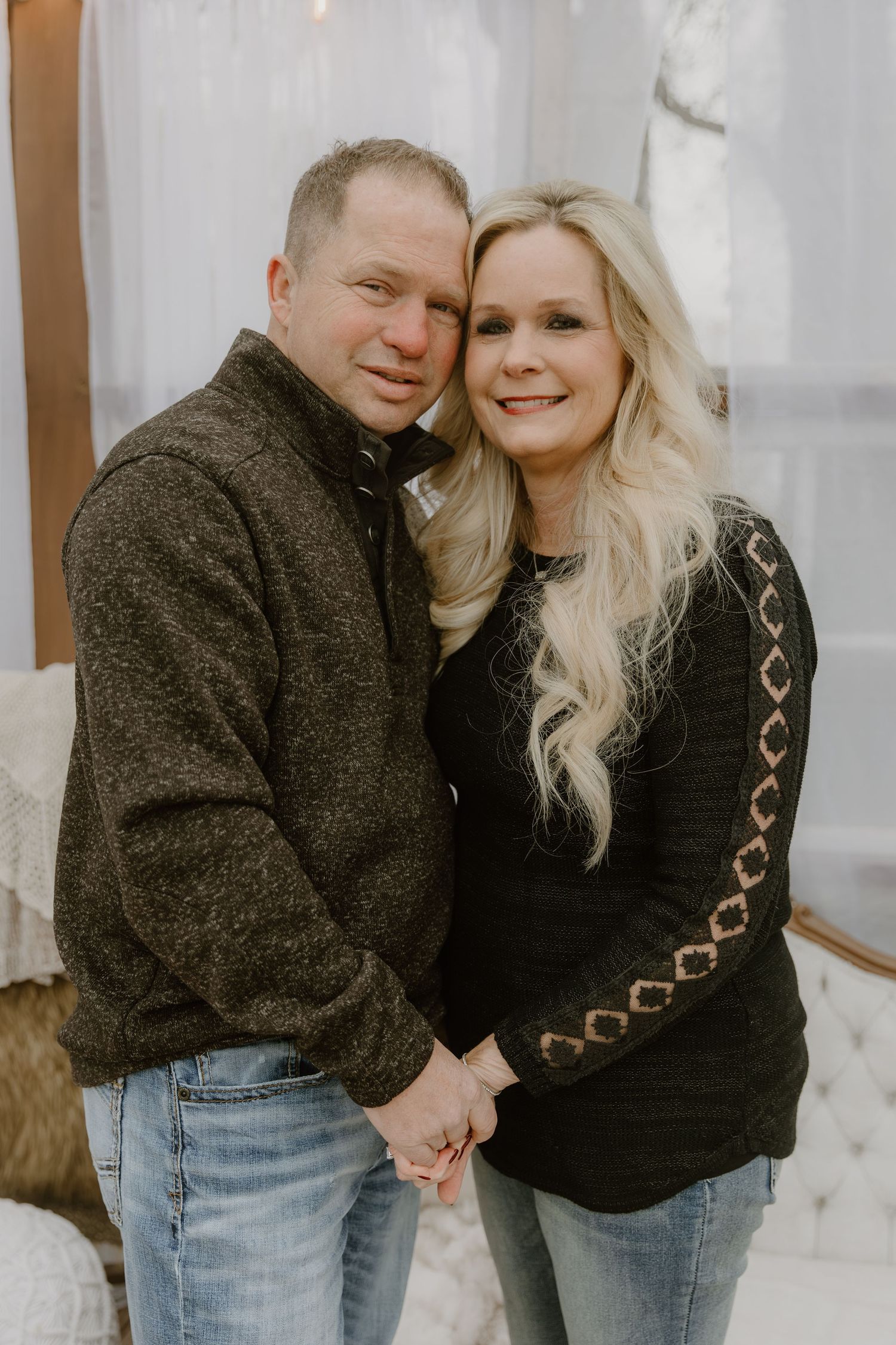 A couple wearing matching dark sweaters and jeans poses together in a series of candid romantic shots.