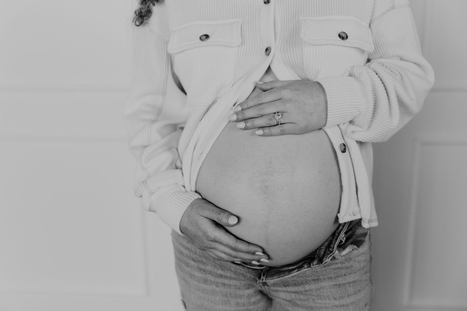 A series of black and white photos showing a pregnant woman's growing belly throughout different stages of pregnancy.
