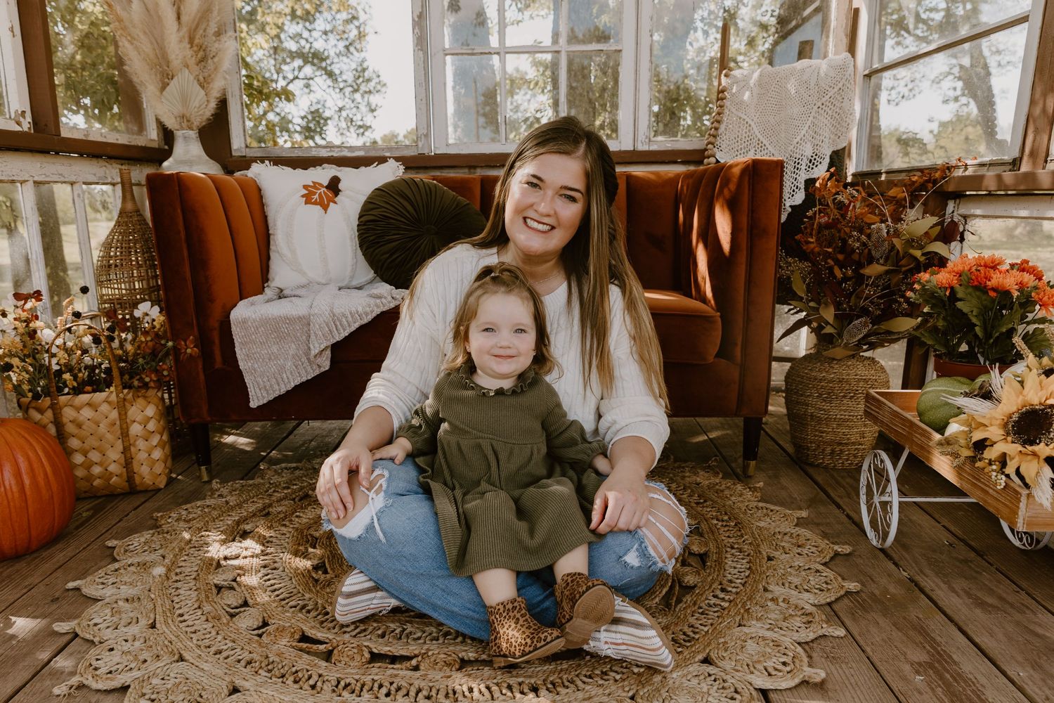 A cozy fall photo session featuring pumpkins, blankets and warm autumn decor on a rustic wooden porch.