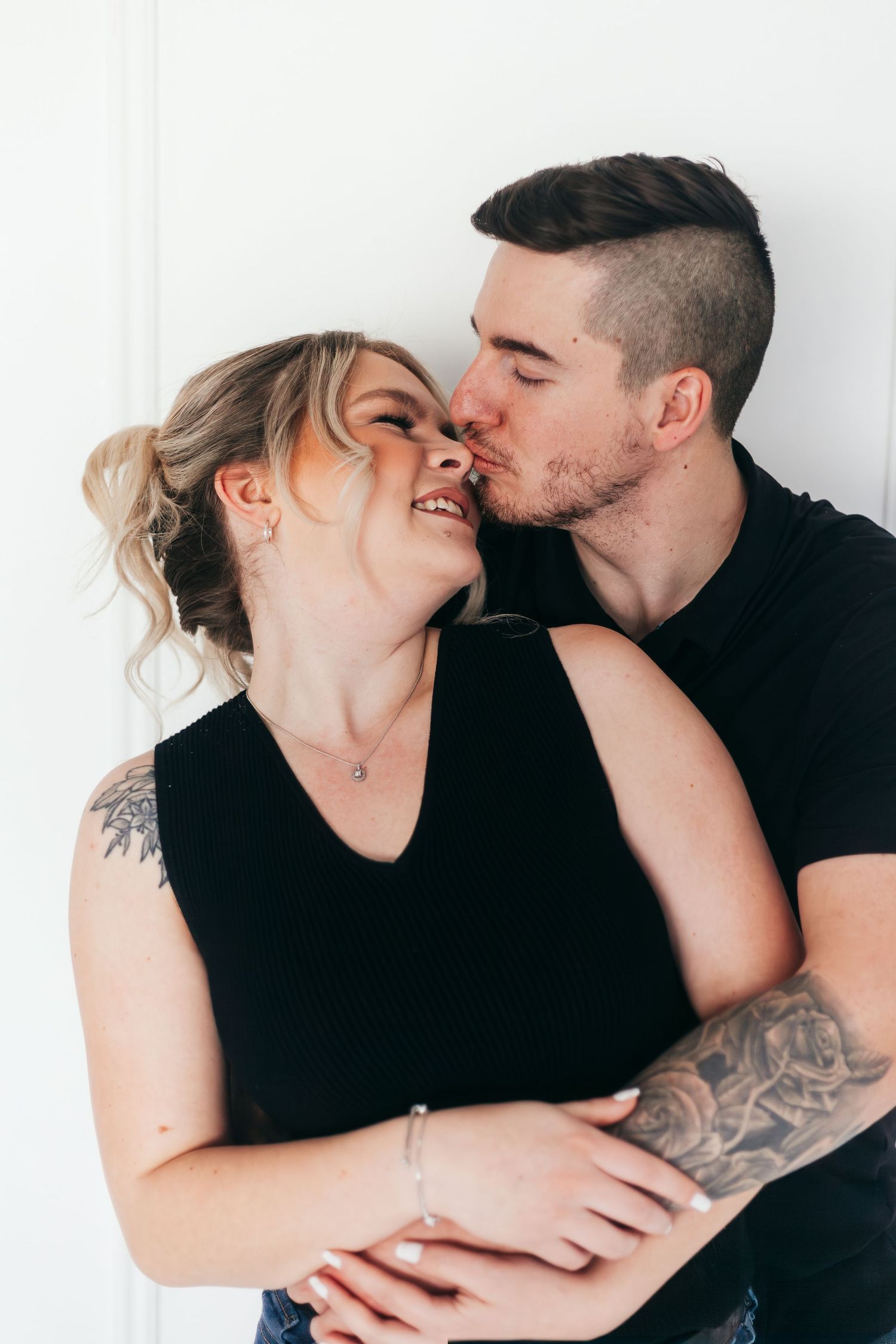 A couple shares romantic and intimate moments in a black and white photo series against a white background.