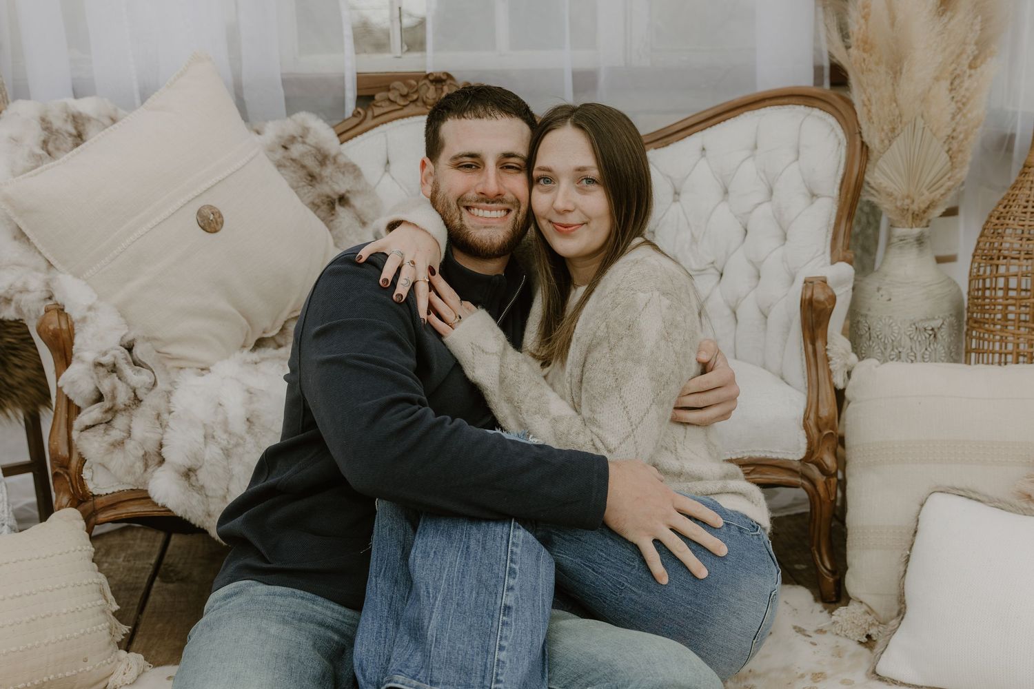A couple shares intimate moments in a cozy indoor setting with neutral toned decor and soft lighting.