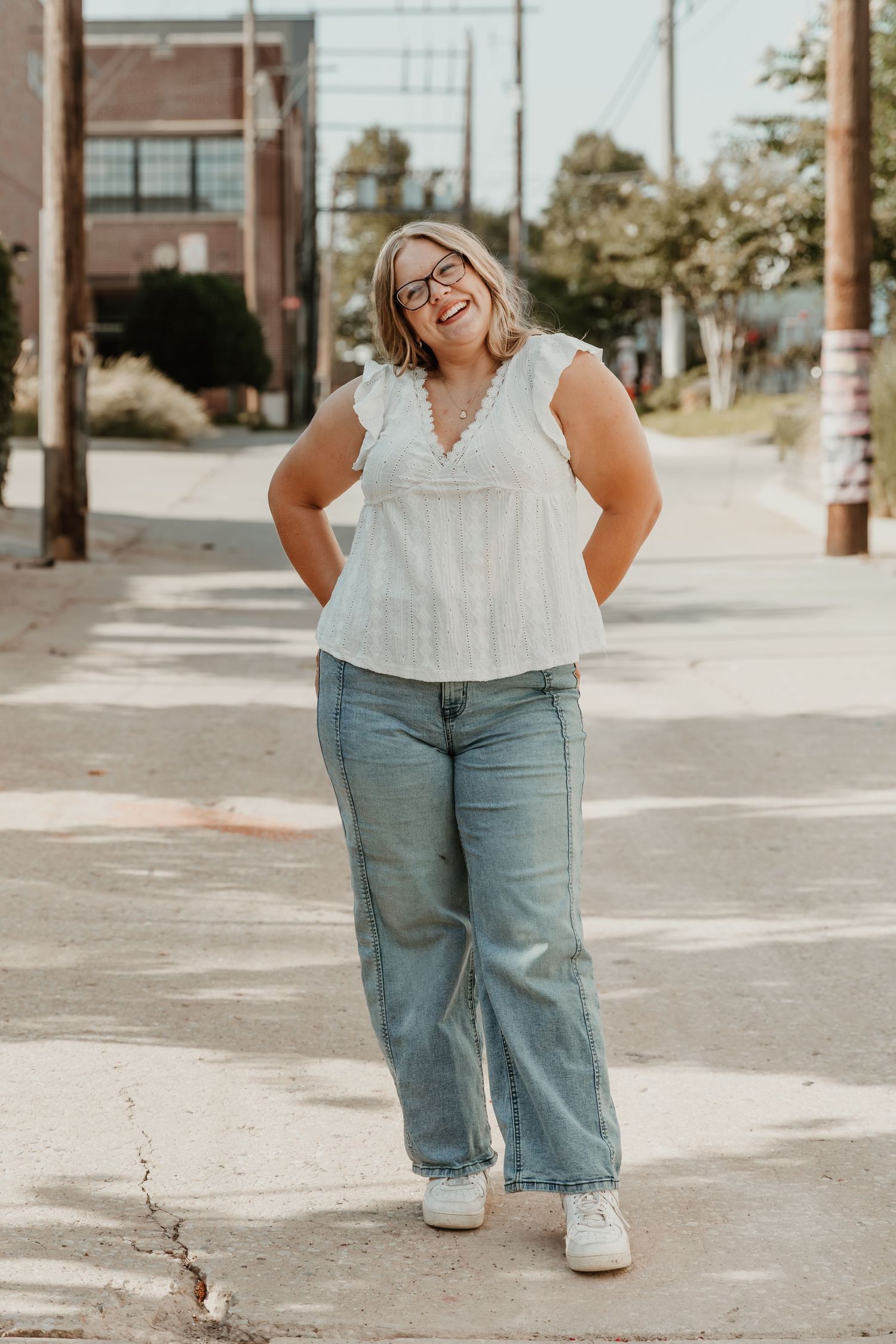 A casual urban photo series featuring light denim jeans and a white ruffled top on a sunny sidewalk.