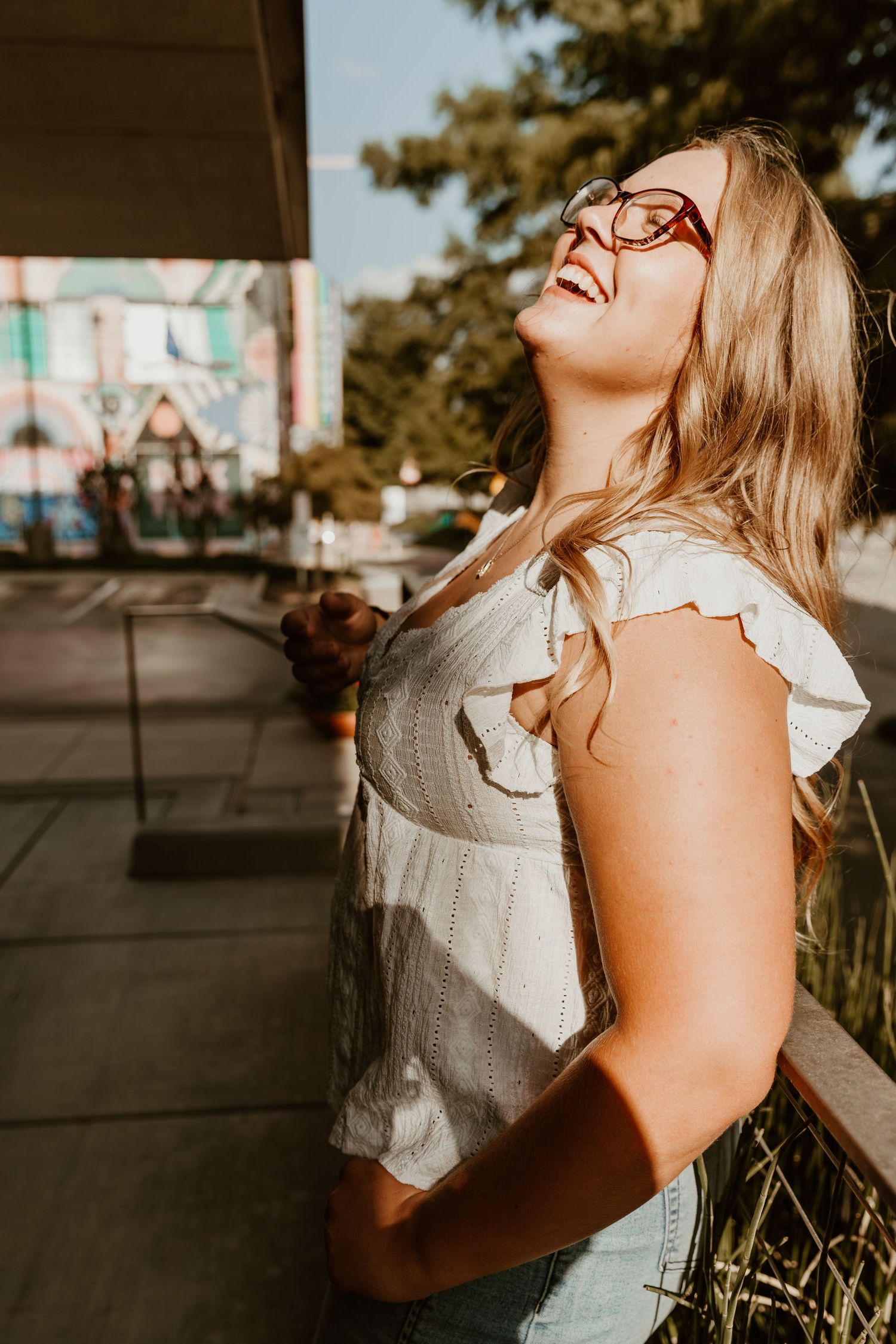 Woman in white sleeveless top laughing joyfully in a series of outdoor portrait shots at golden hour.