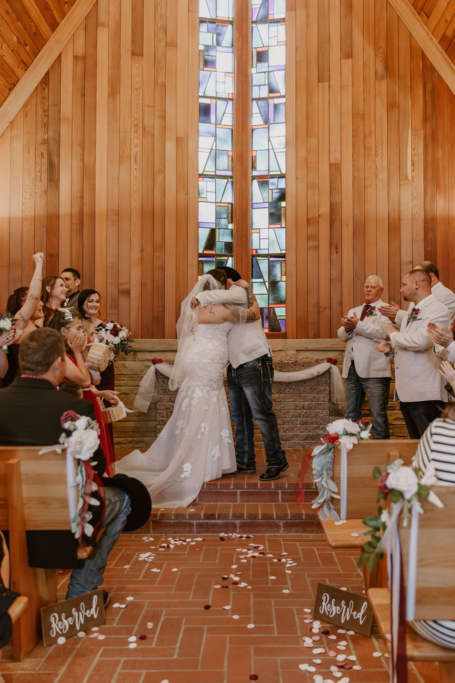 Wedding couple and guests enjoy a playful bubble-filled reception dance at a rustic wooden venue with stone accents.