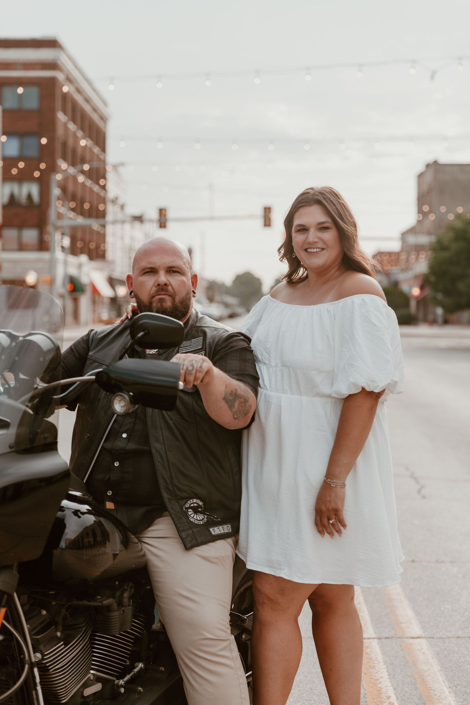 A couple poses with a motorcycle in the street, sharing romantic and playful moments across multiple urban photo shots.