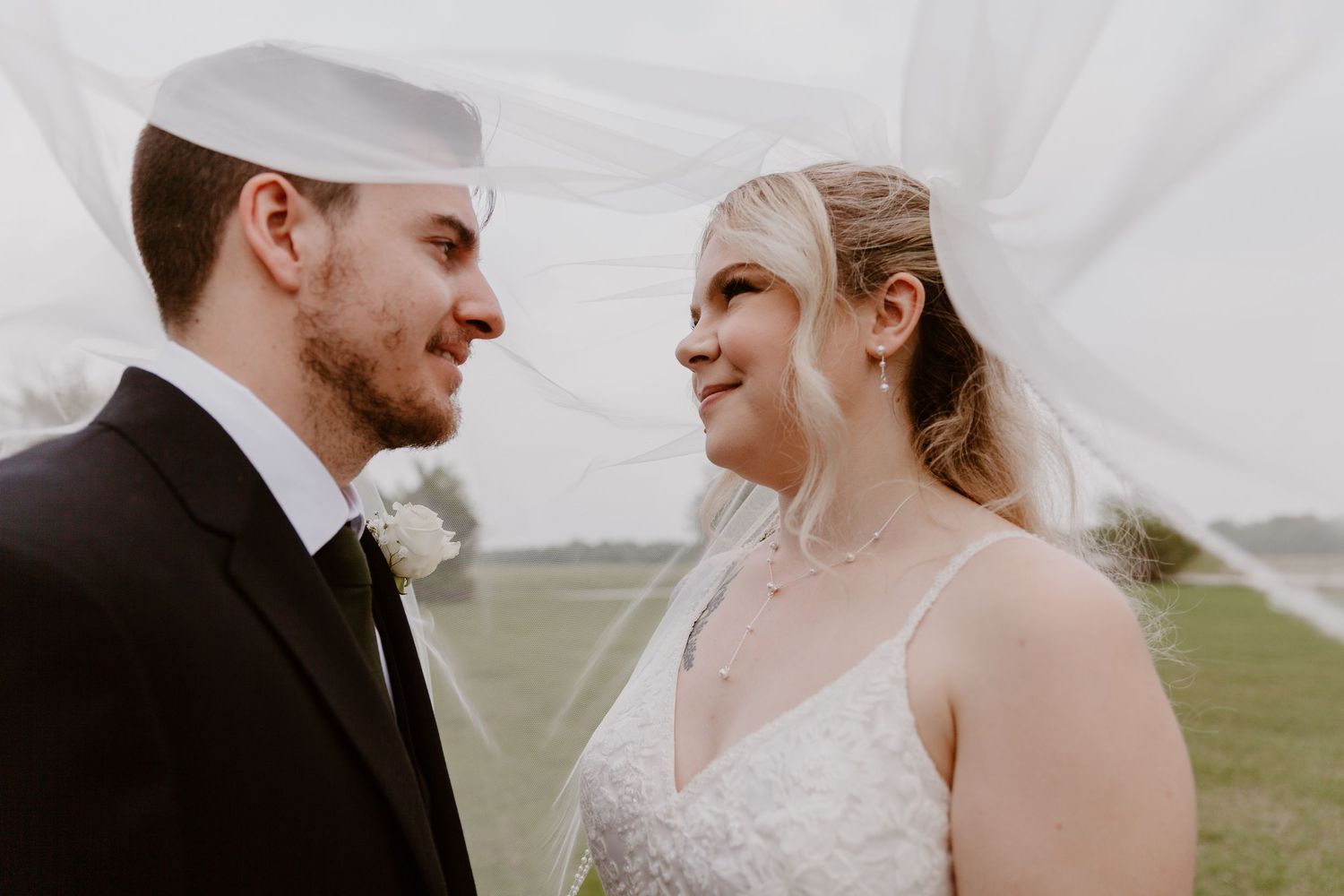 A couple shares a joyful moment on their wedding day at an outdoor venue under cloudy skies.