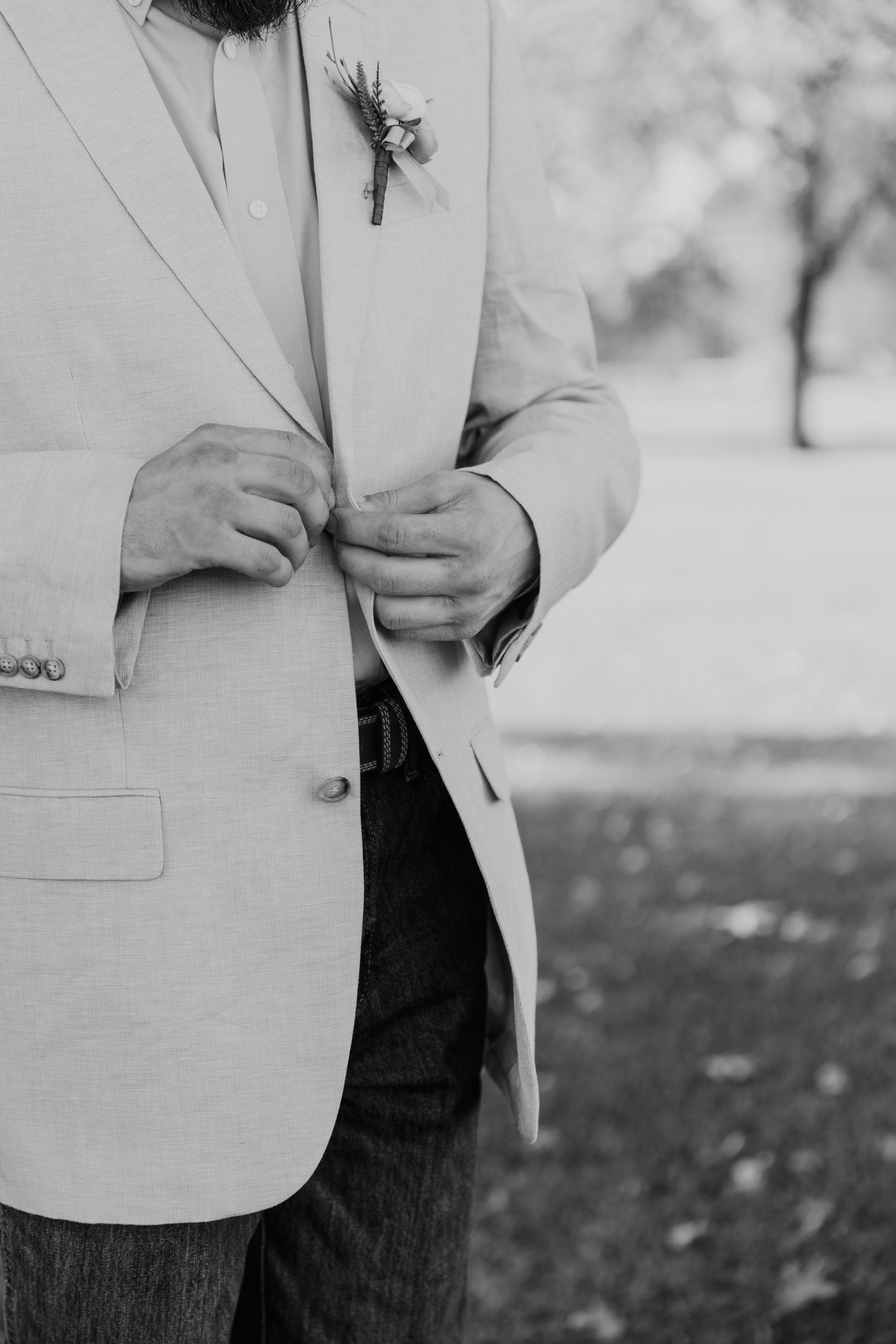 Close-up view of a light beige blazer and dark jeans in a minimalist black and white photograph.