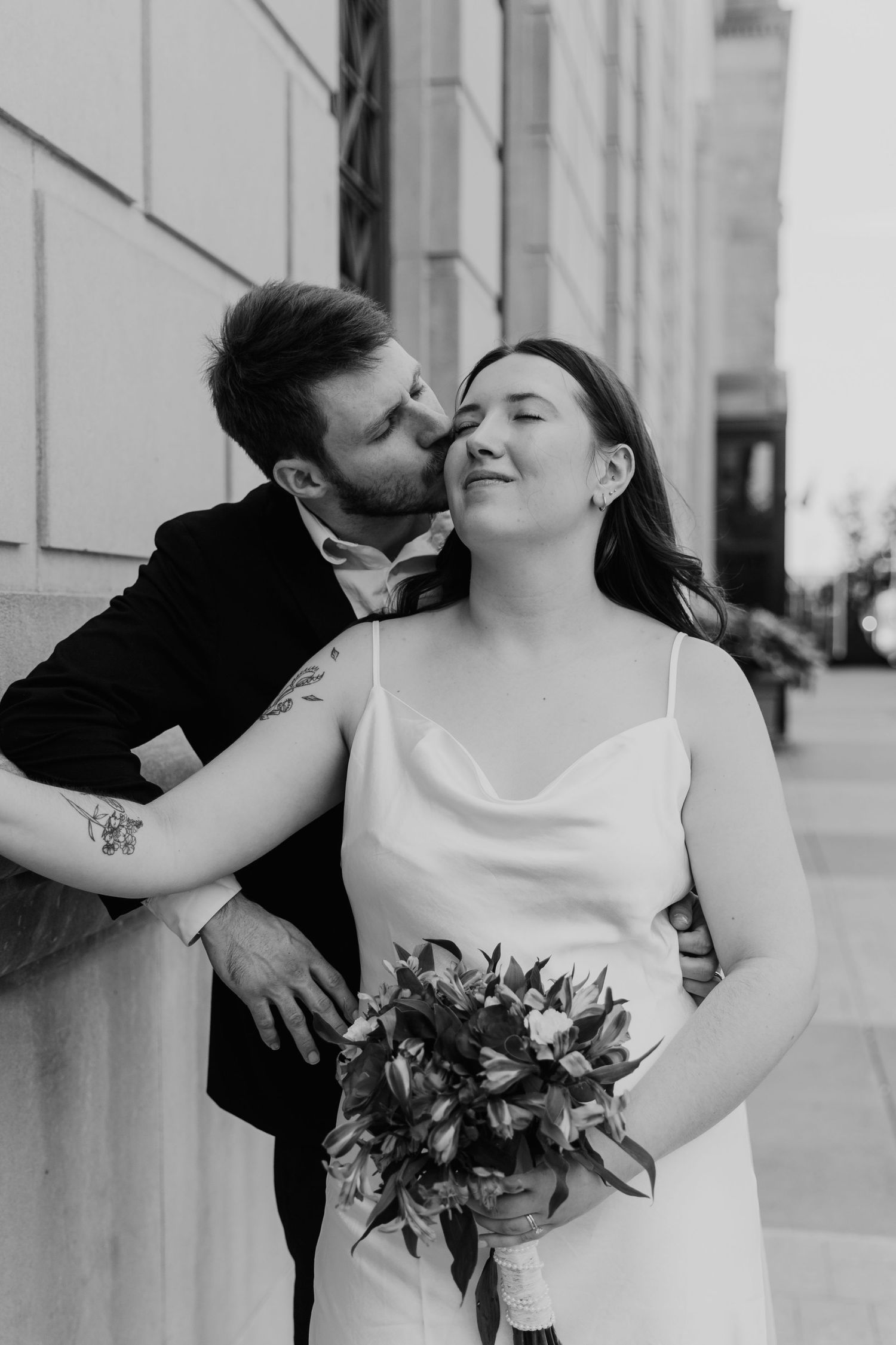 A romantic black and white photo sequence showing a couple embracing and kissing while holding a floral bouquet.