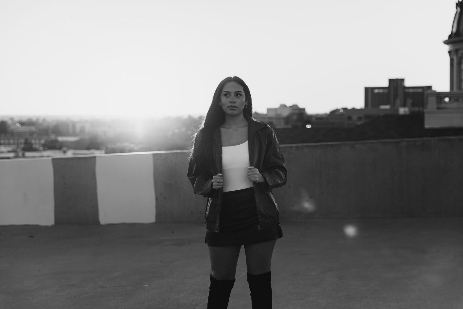 A person stands in silhouette against a bright sunset sky on a rooftop.