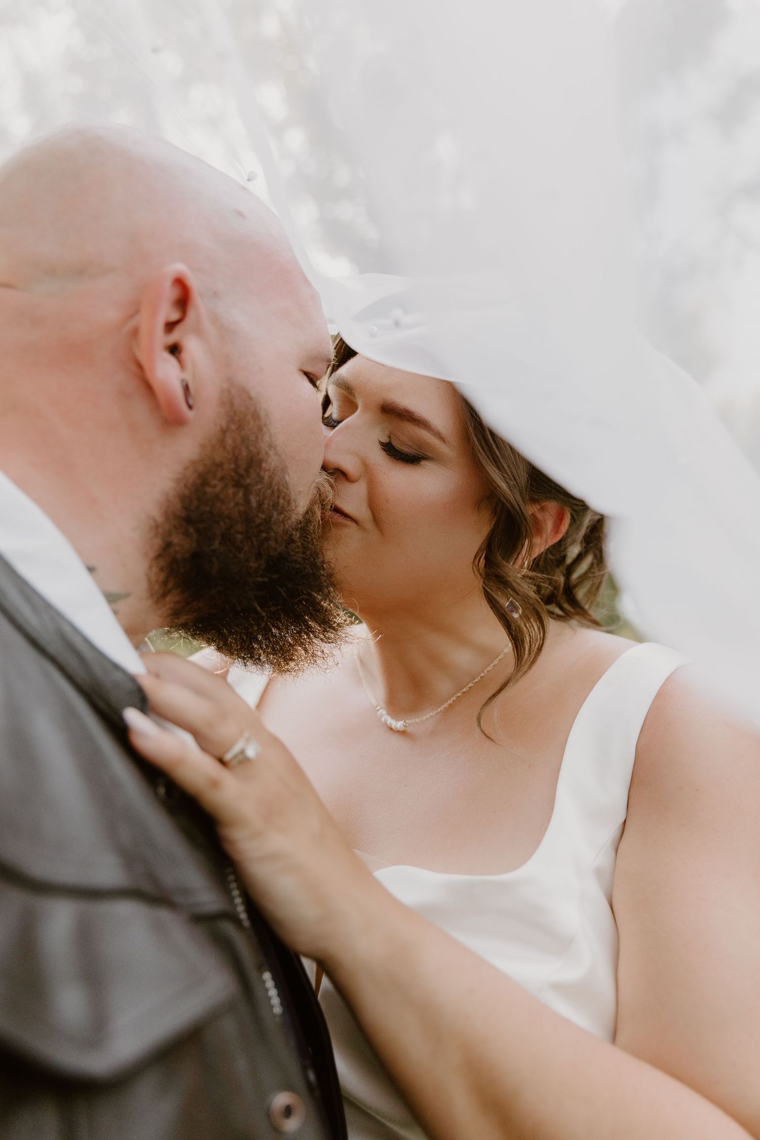 Close-up photograph of a romantic couple sharing an intimate kiss against a light background.