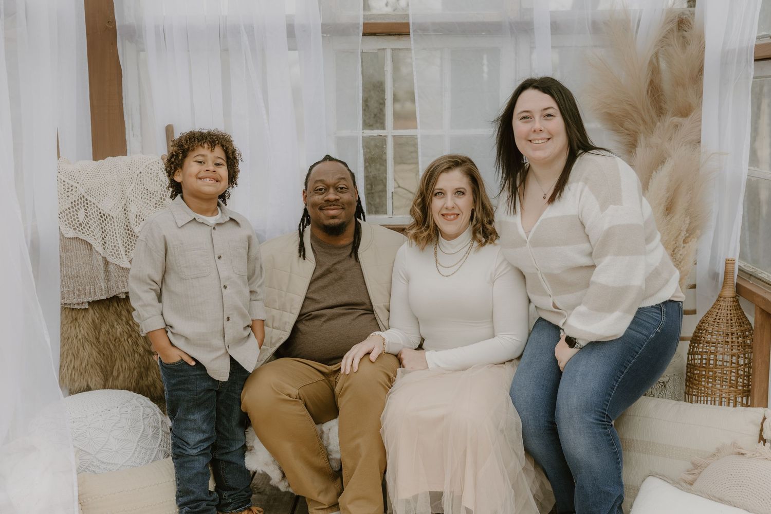 A diverse group sits together on a white couch in a bright, airy room with natural decor.