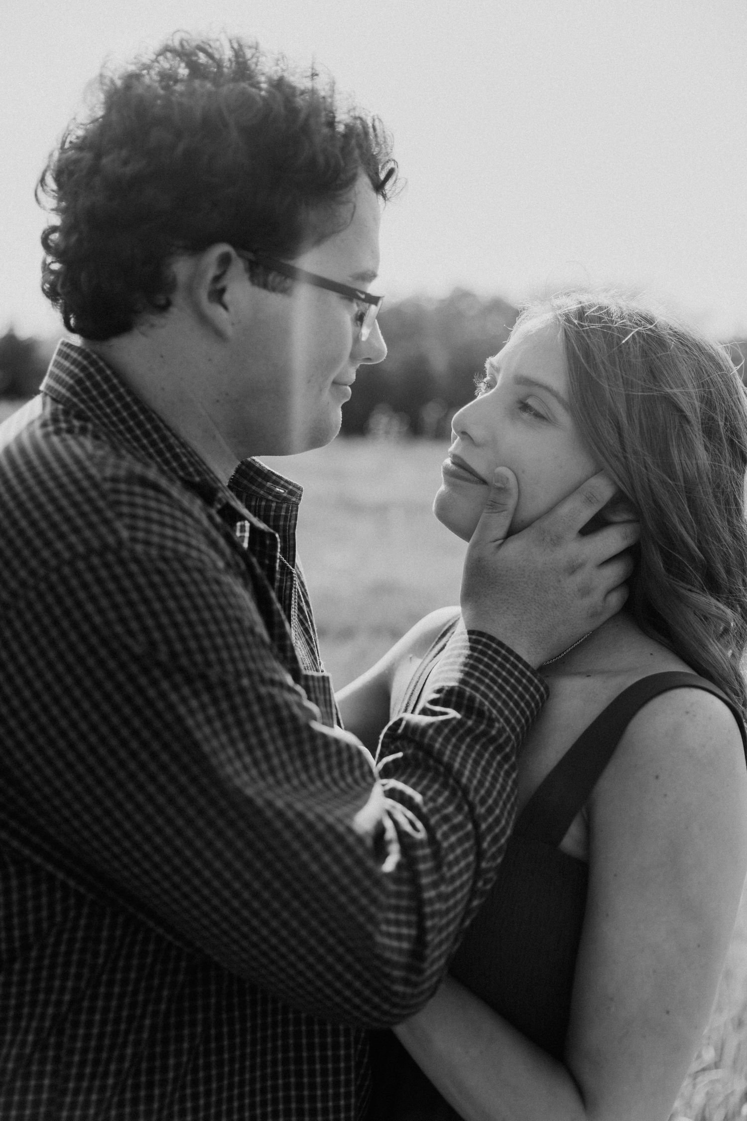 Black and white photo of a couple sharing an intimate moment in a natural outdoor setting.