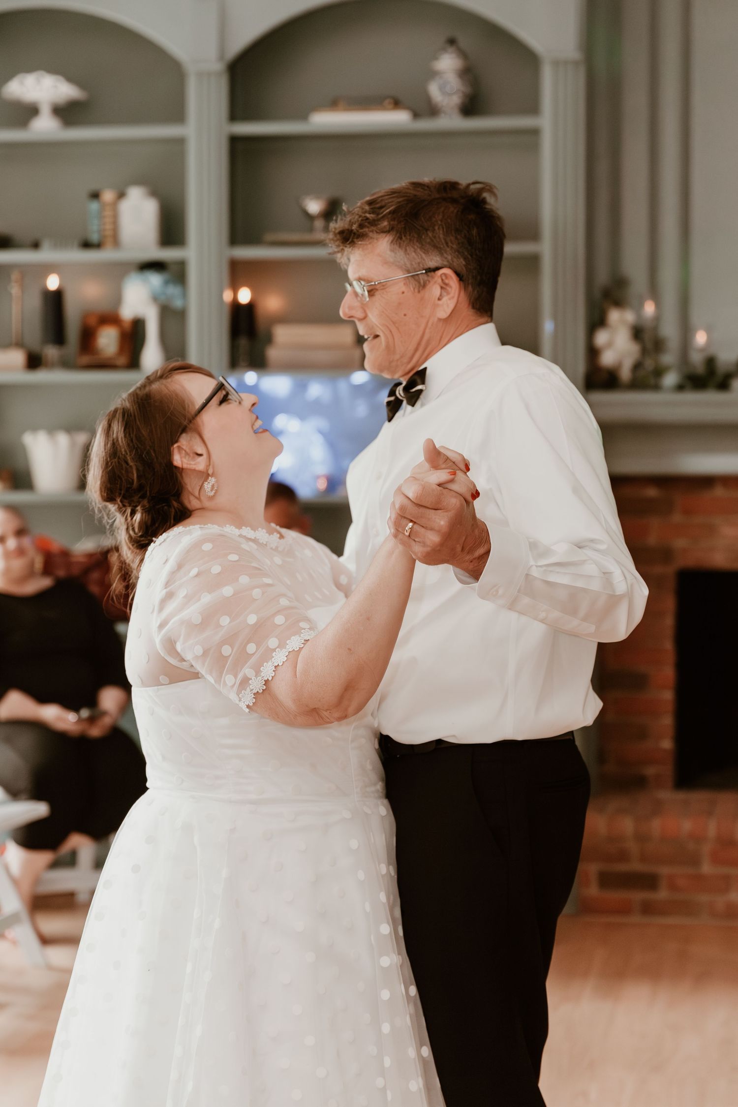 Two people dance and smile together in a wedding ceremony showing joy and affection at an indoor venue.