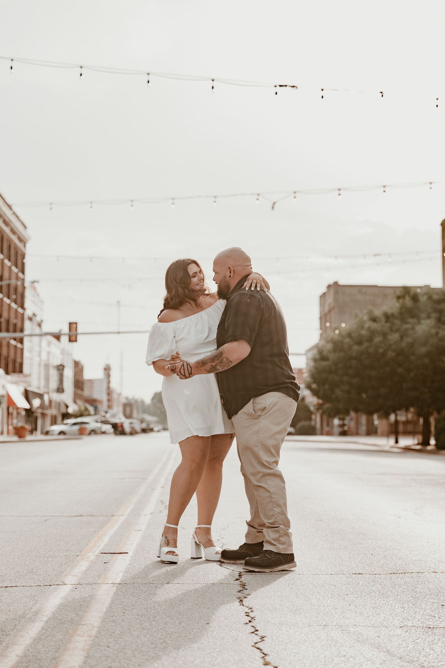 A romantic couple sharing an intimate dip and kiss on a quiet small town street during a photo session.