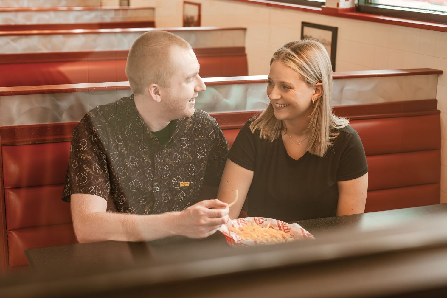 A couple shares pizza together at a casual restaurant booth.