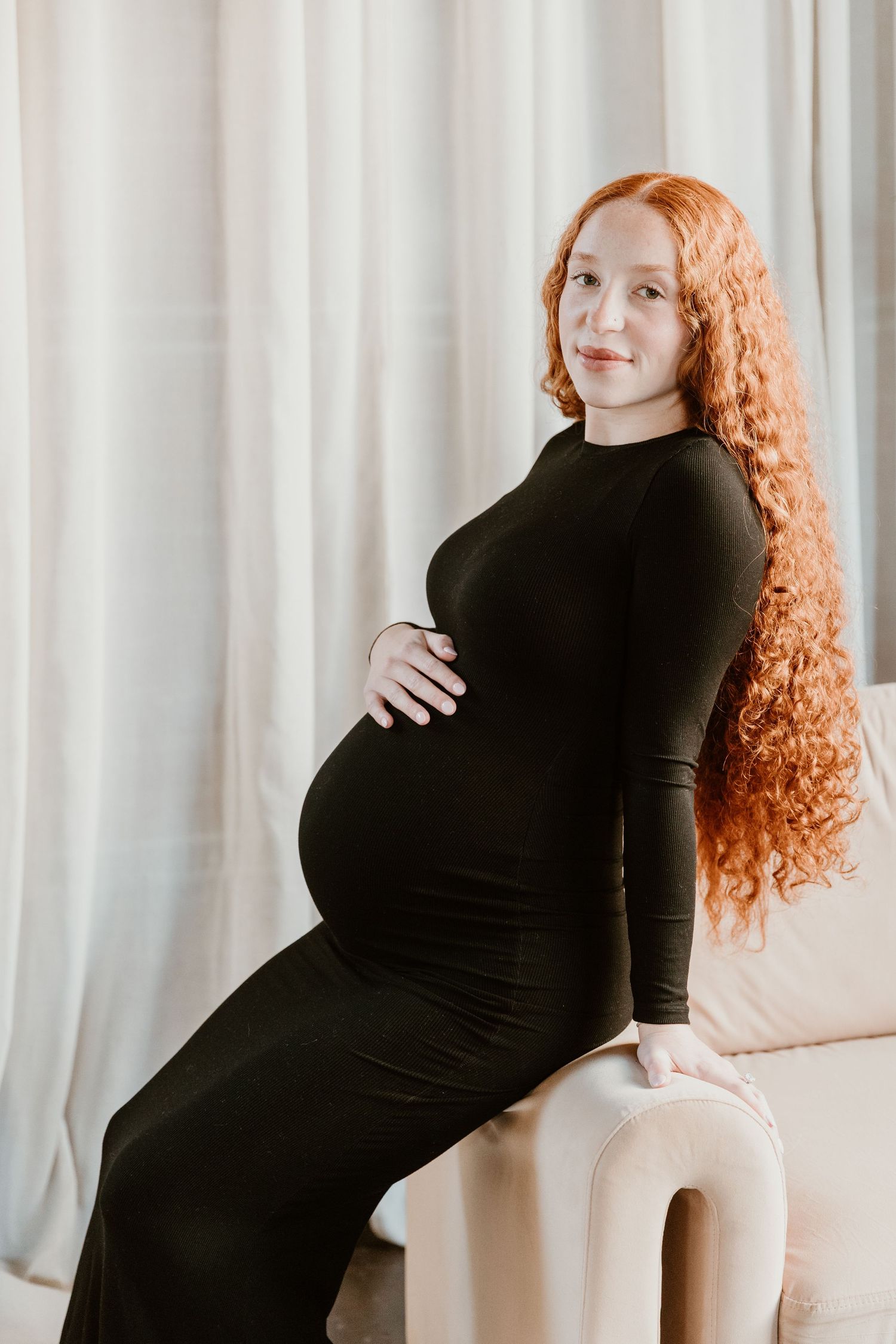 A pregnant woman in a black dress poses in a series of artistic maternity photos against a light background.