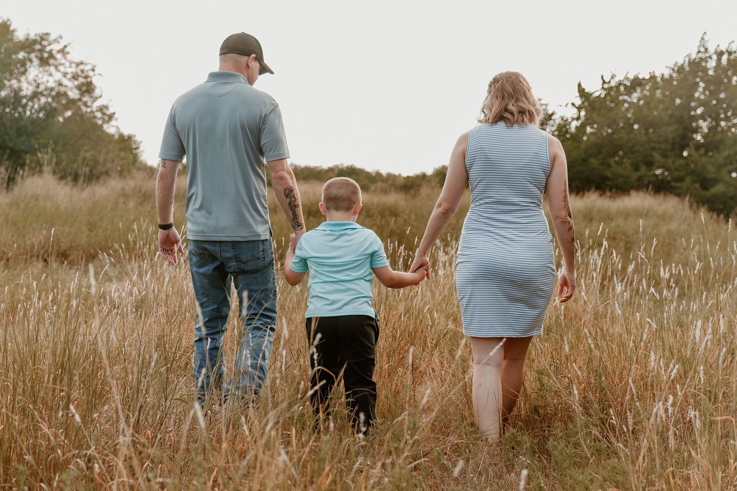 Four images showing people holding hands while walking through tall golden grass in an outdoor field at sunset.
