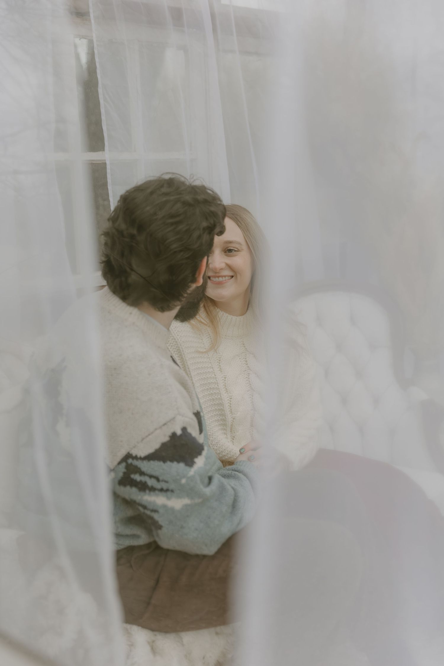A romantic couple embraces behind sheer white curtains in a dreamy, ethereal photoshoot sequence.